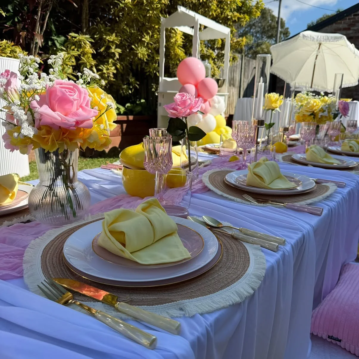 Pink and yellow picnic table styling with fresh roses and gold cutlery