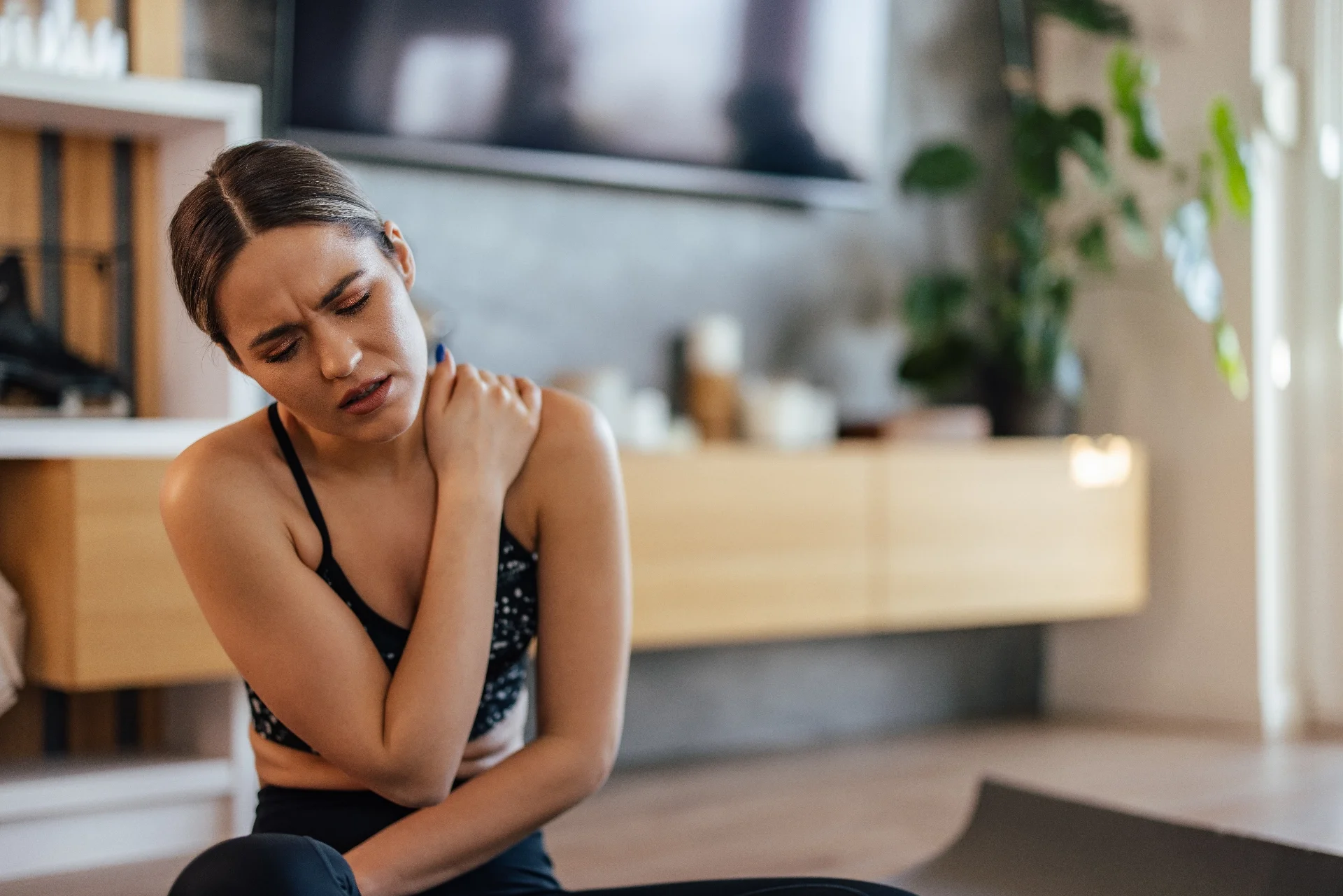 Woman holding her neck and shoulder, showing recurring neck pain and shoulder tension