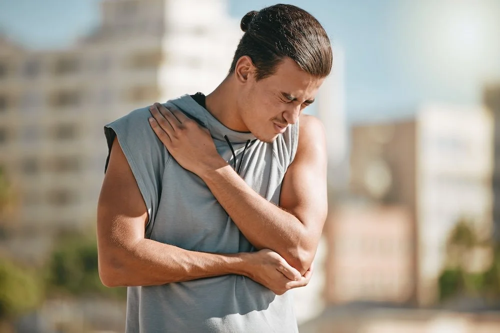 Young man holding his chest and abdomen, representing discomfort and protective tension during recovery.