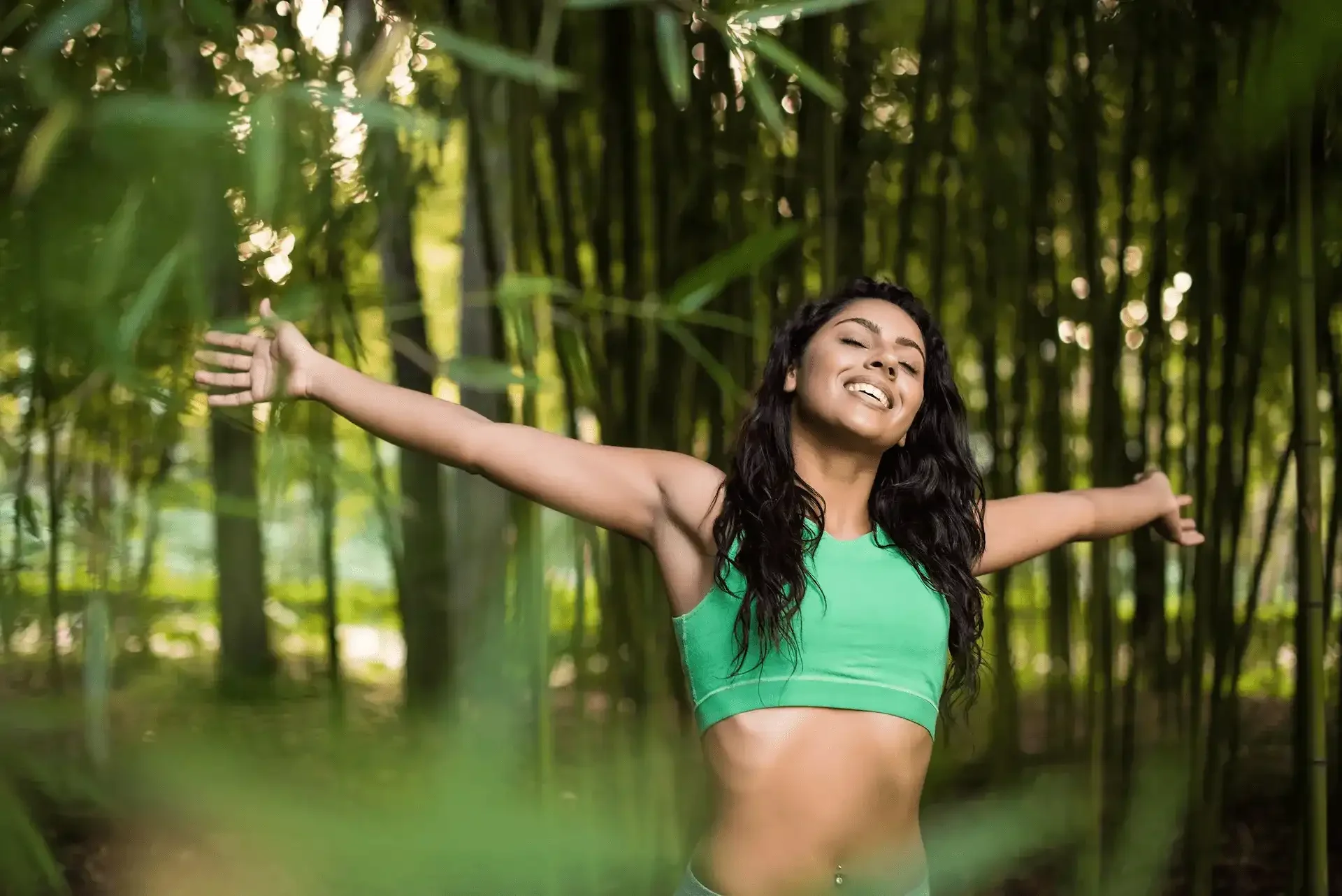 Woman stretching outdoors in nature, representing body awareness and movement support at LifeSTATE Clinic in Nelson.