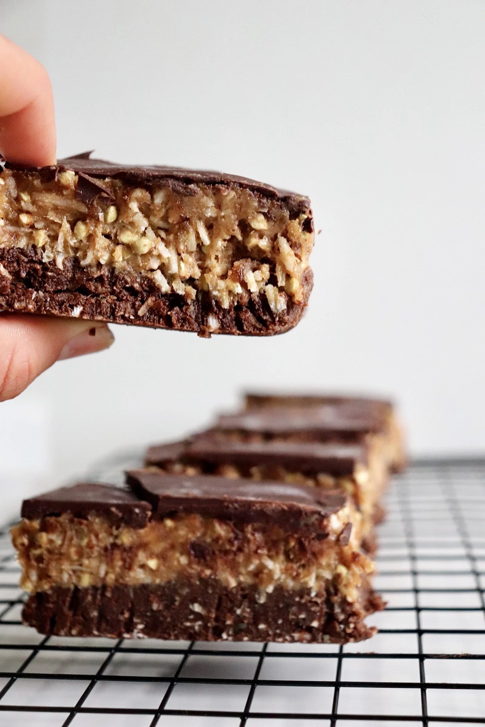 Layered chocolate and nut dessert bars cooling on a wire rack.