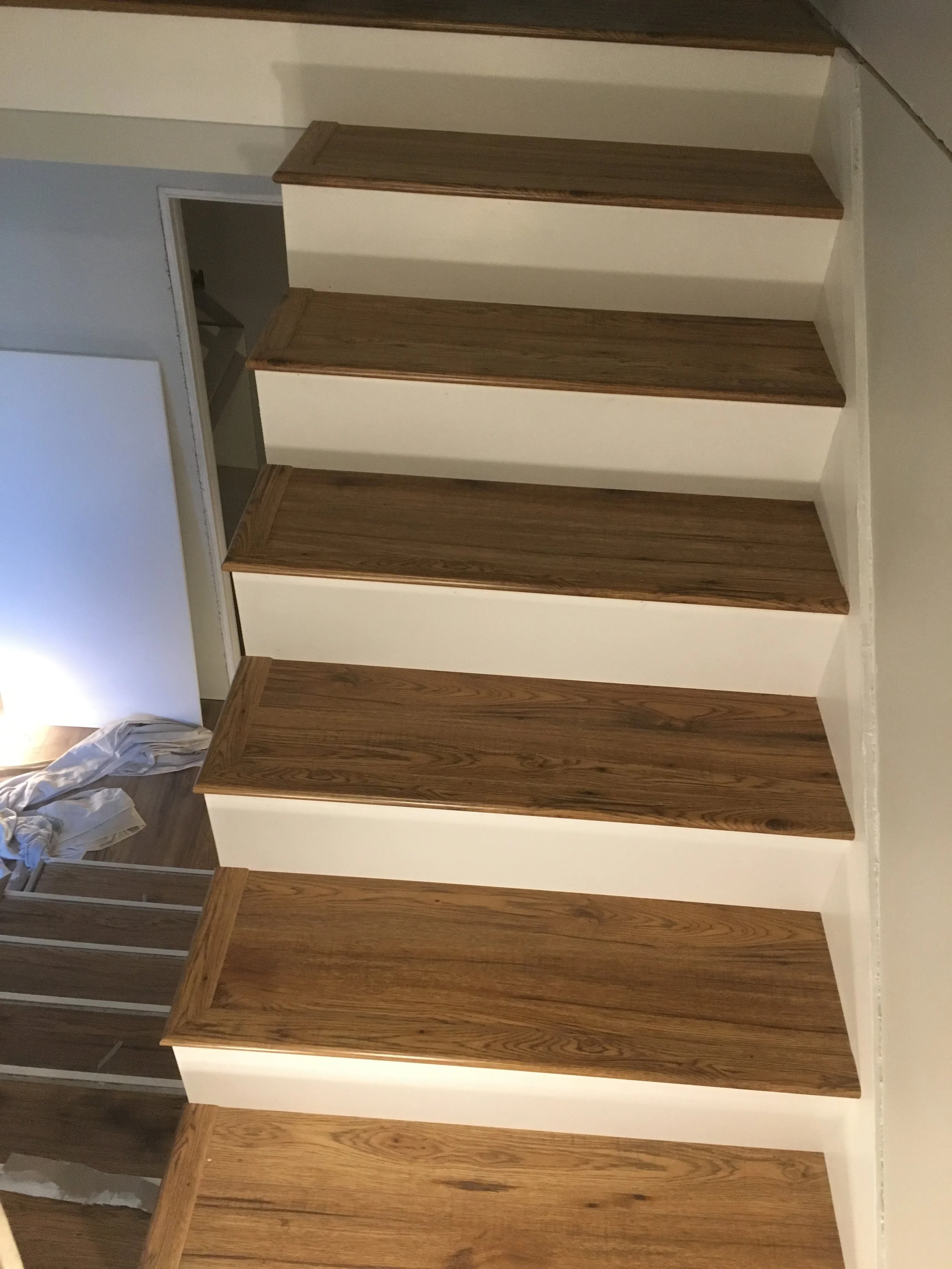A staircase with wooden handrails and white risers, leading upwards along a wall.