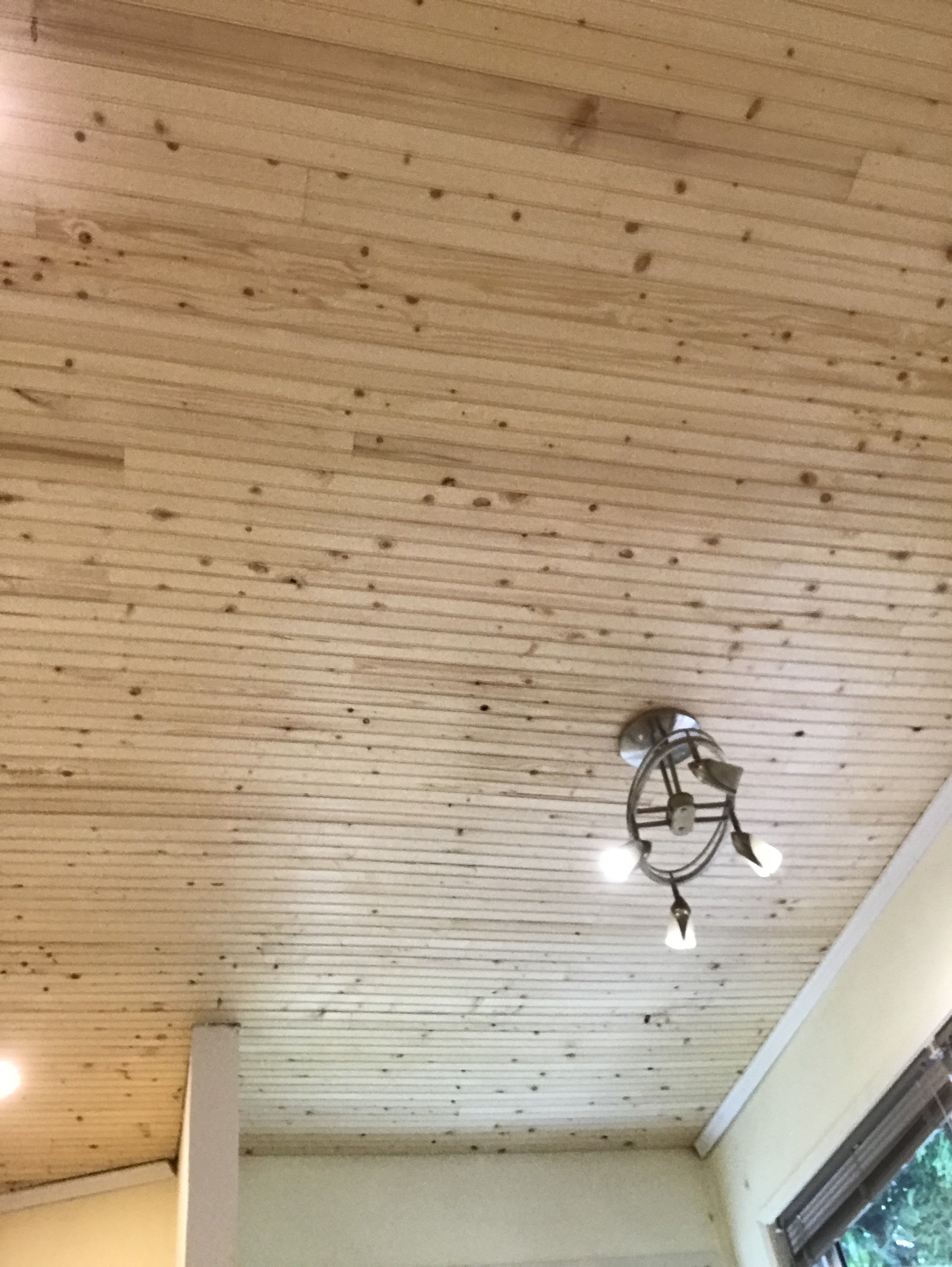 Wooden ceiling with visible nail holes and a ceiling light fixture with three bulbs.