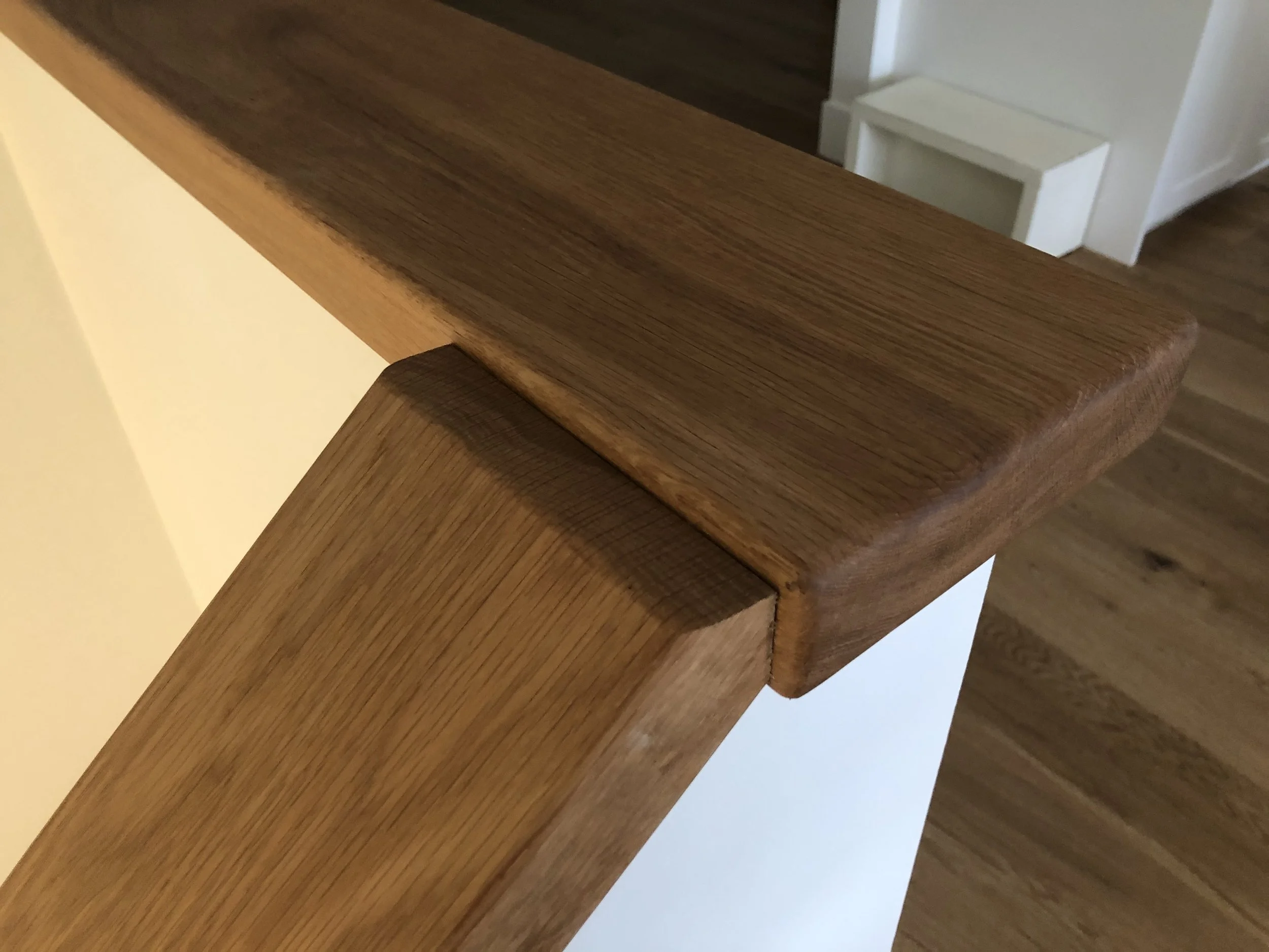 Close-up of a wooden staircase with dark brown steps and a light beige wall.