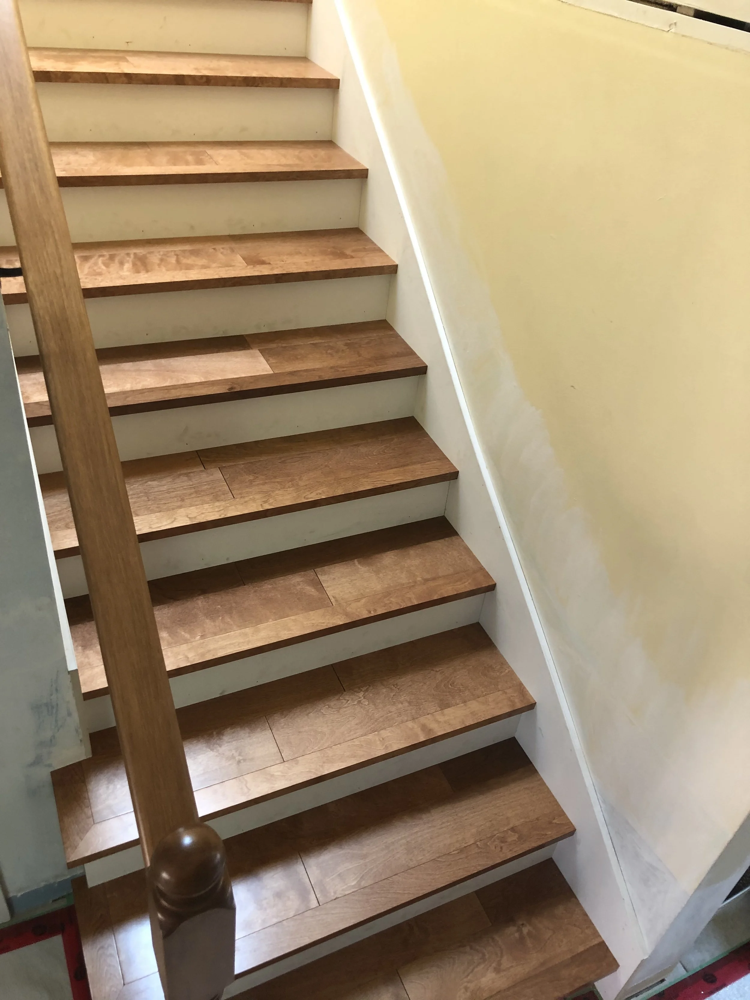 Wooden staircase with seven steps, white risers, and yellow walls on either side.