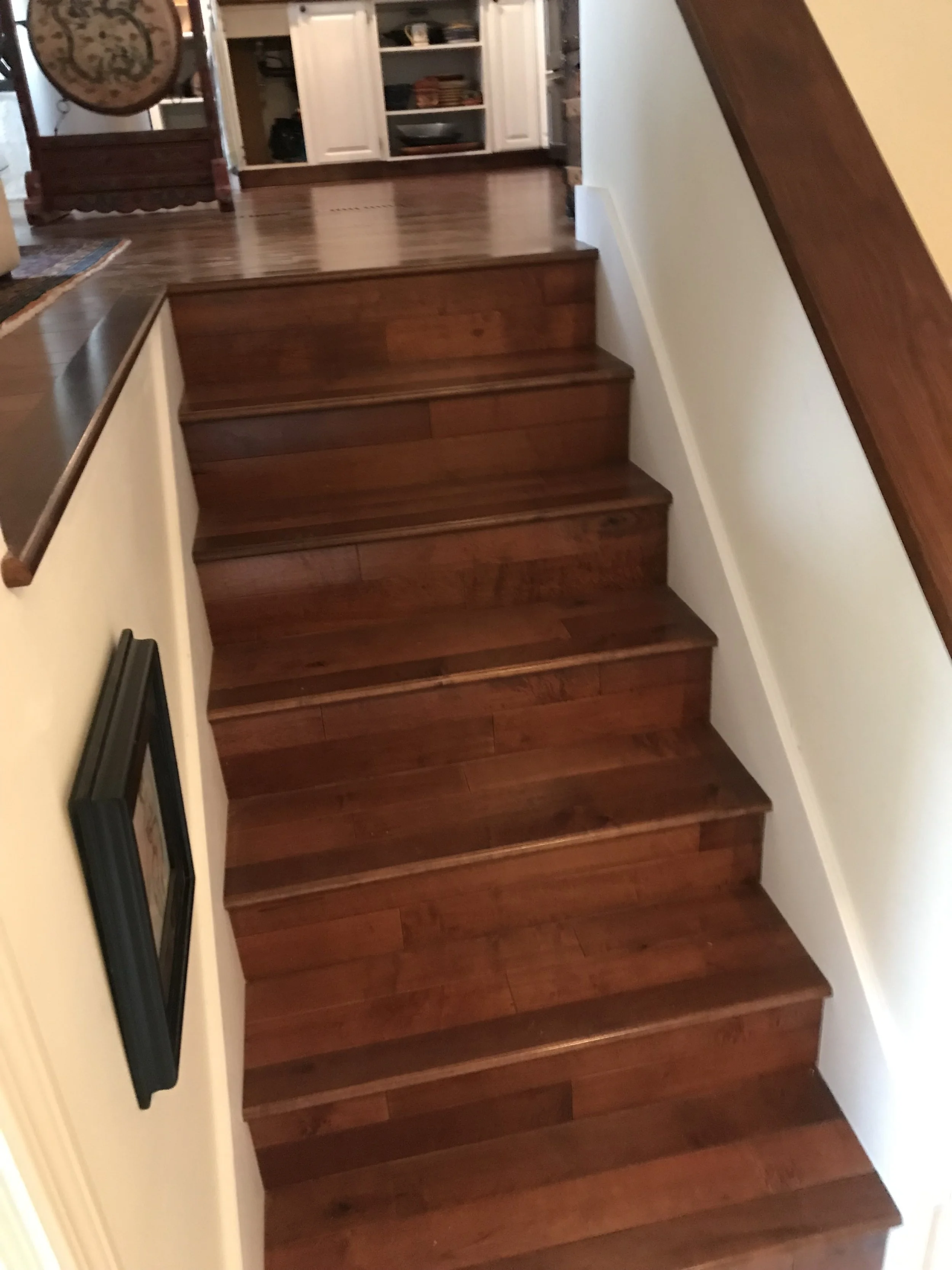 Wooden staircase with brown steps and white walls.