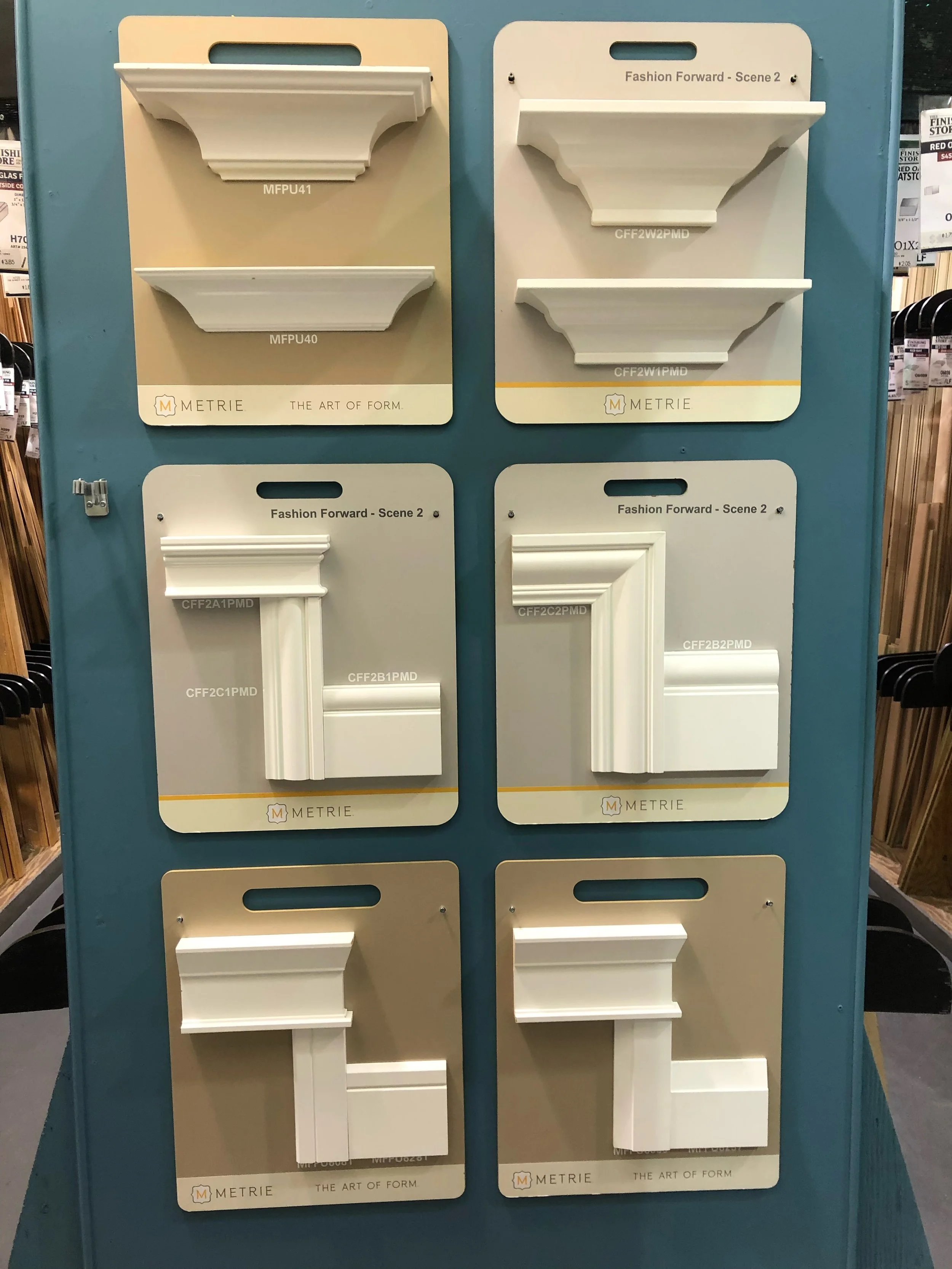 Display of white decorative moulding samples mounted on blue display boards in a store.