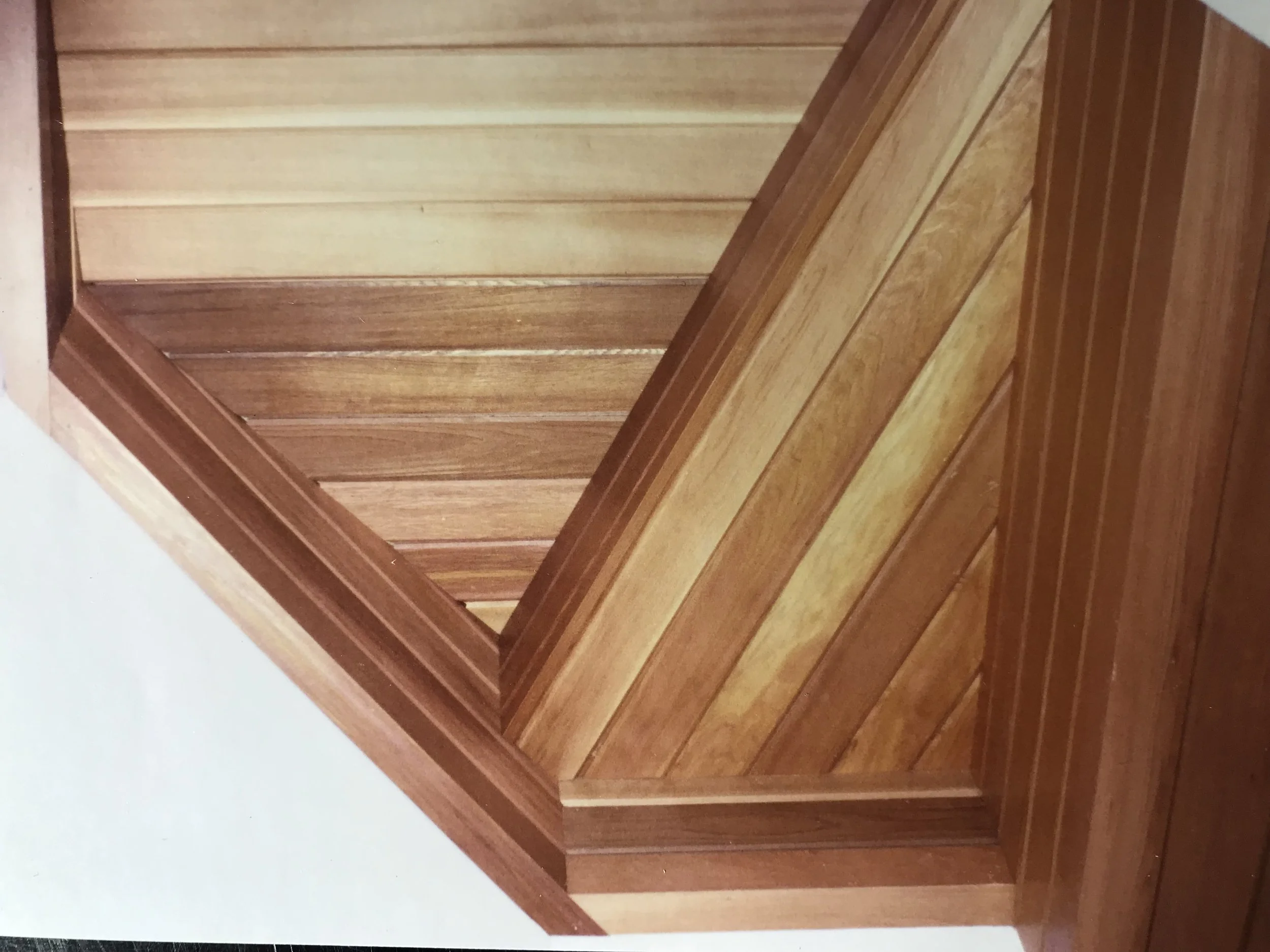 A wooden staircase with brown finish, viewed from an angle showing the steps and railing.