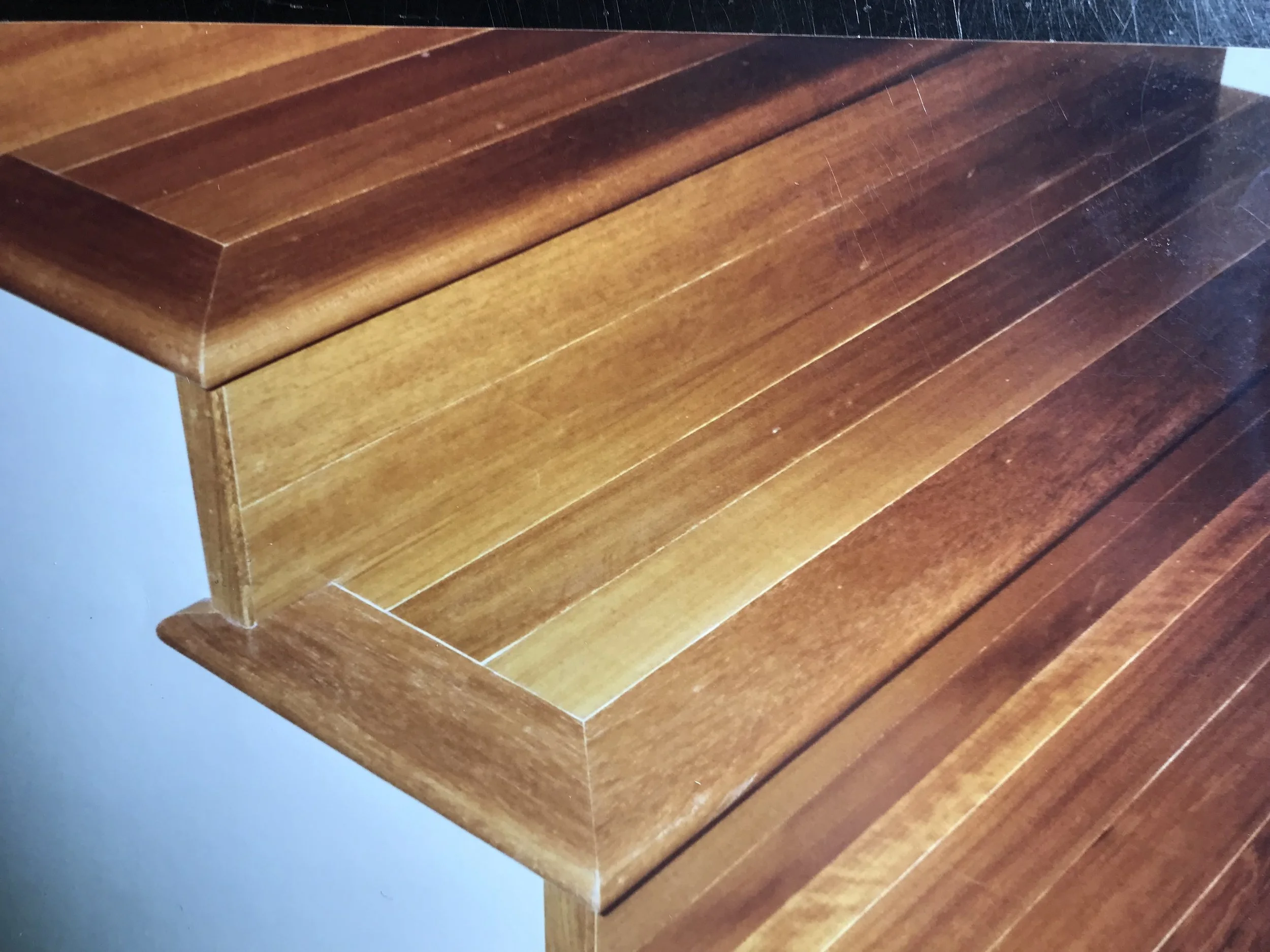 Wooden table with a polished surface and rounded edges, corner view showing the grain and finish.