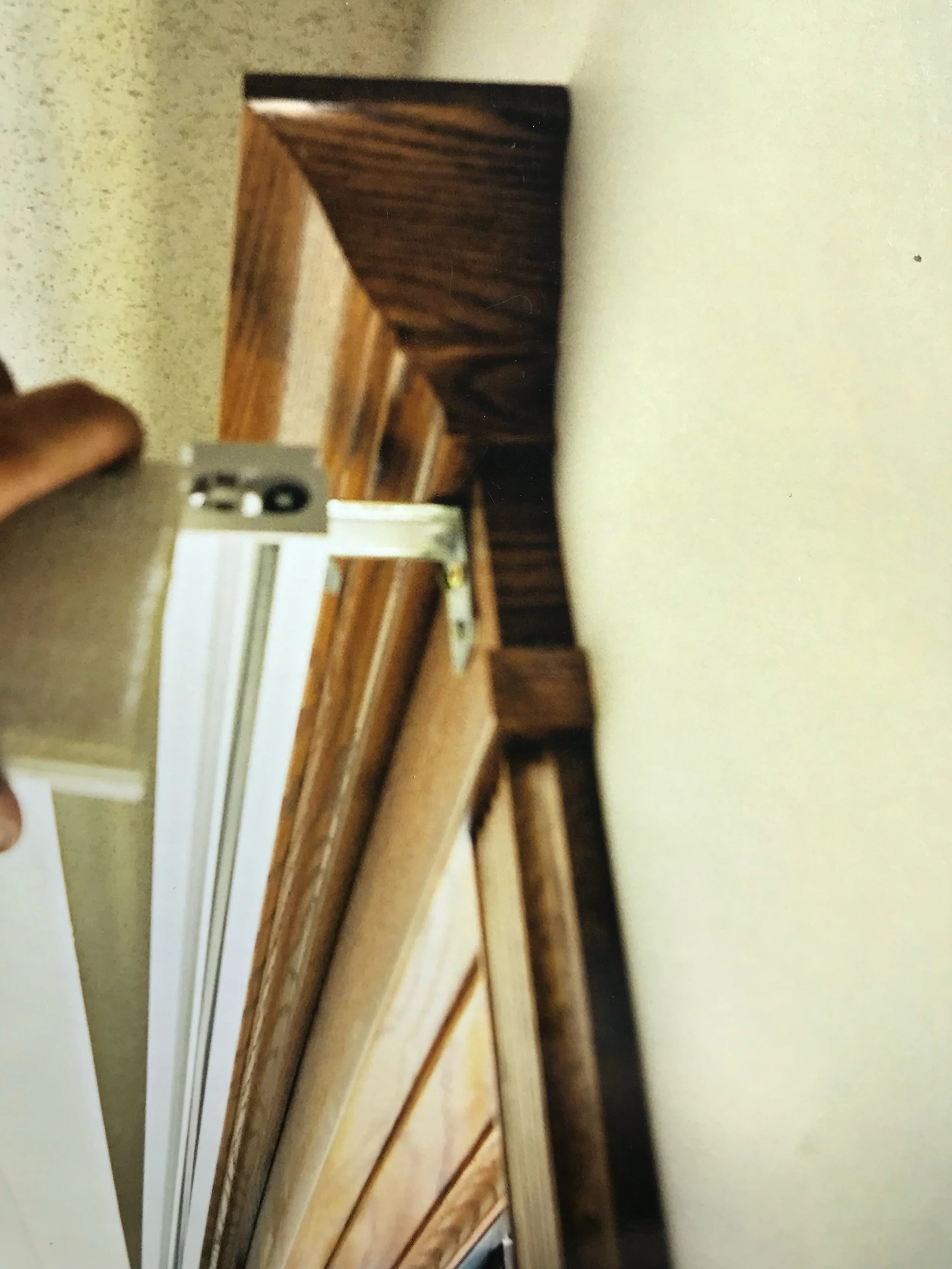 Close-up of a wooden picture frame or decorative molding on a wall, photographed at an angle.