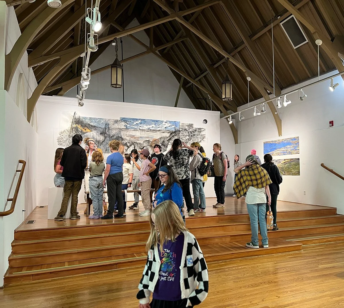 A group of Summer Arts students touring The Art Center exhibit with a large painting in the background