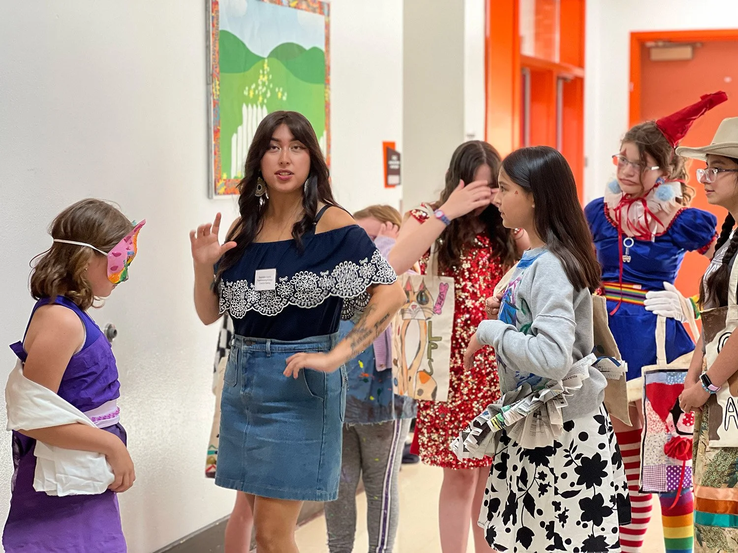 Art teacher with several students in costume preparing for class fashion show