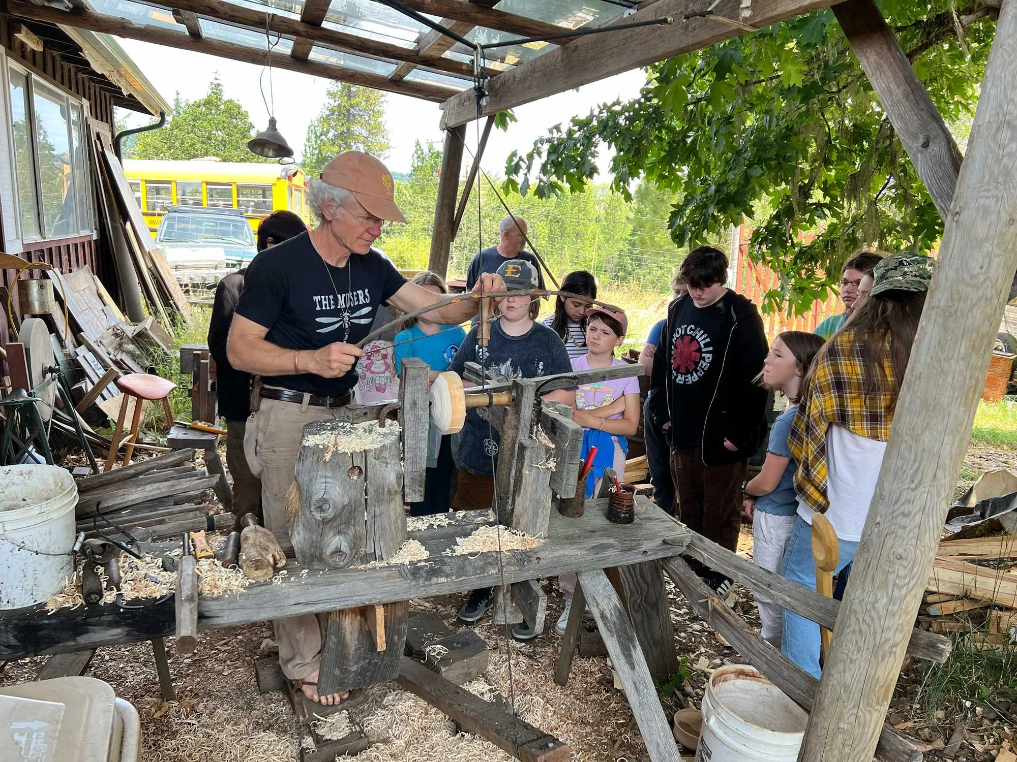 During the 2025 field trip, Kiko Denzer demonstrates handmade woodworking tools and techniques to a group of students outside his studio