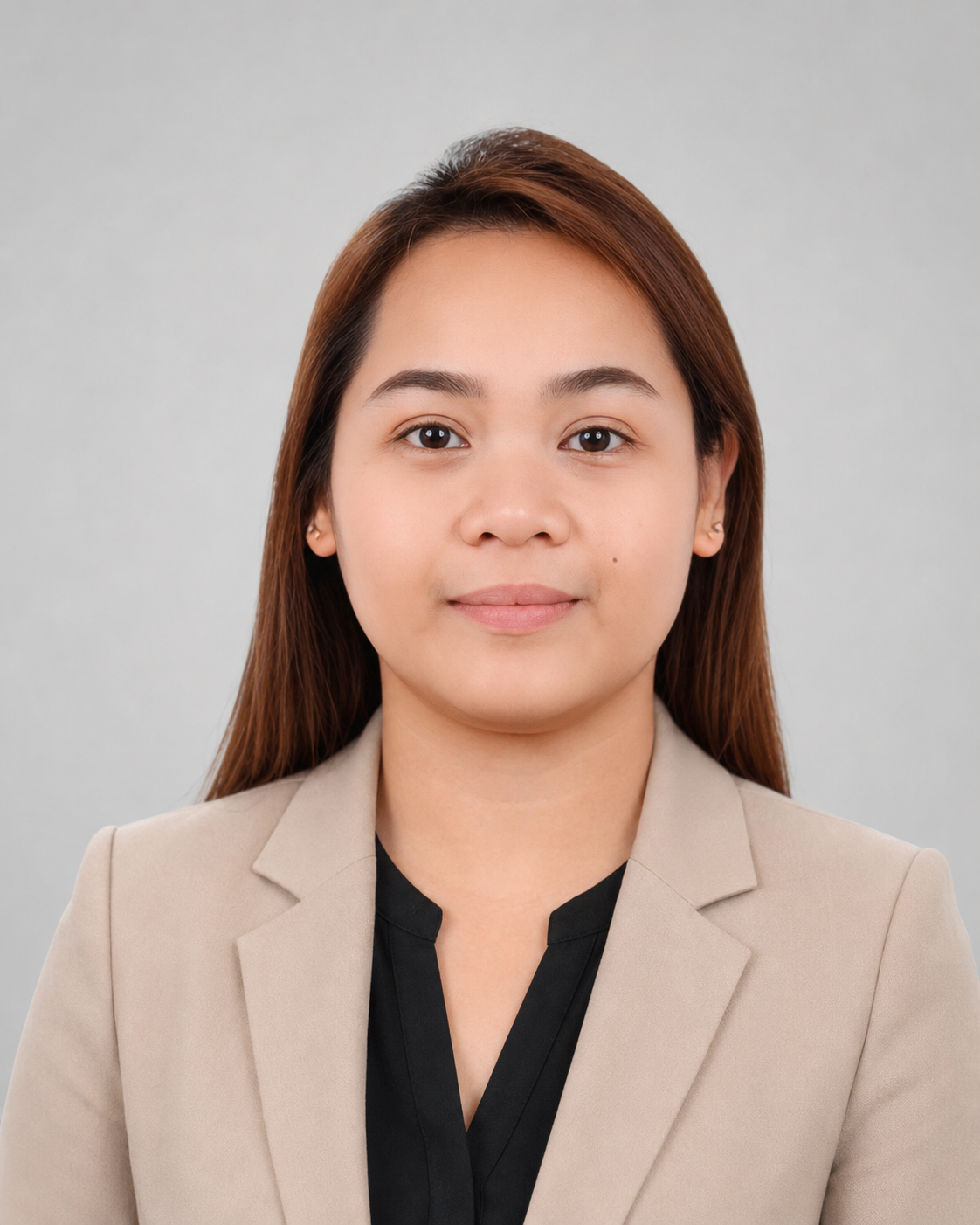 Portrait of a young woman with straight brown hair, wearing a beige blazer and black top, against a plain light gray background.