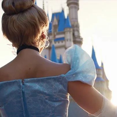 A woman dressed as a princess standing in front of a castle.