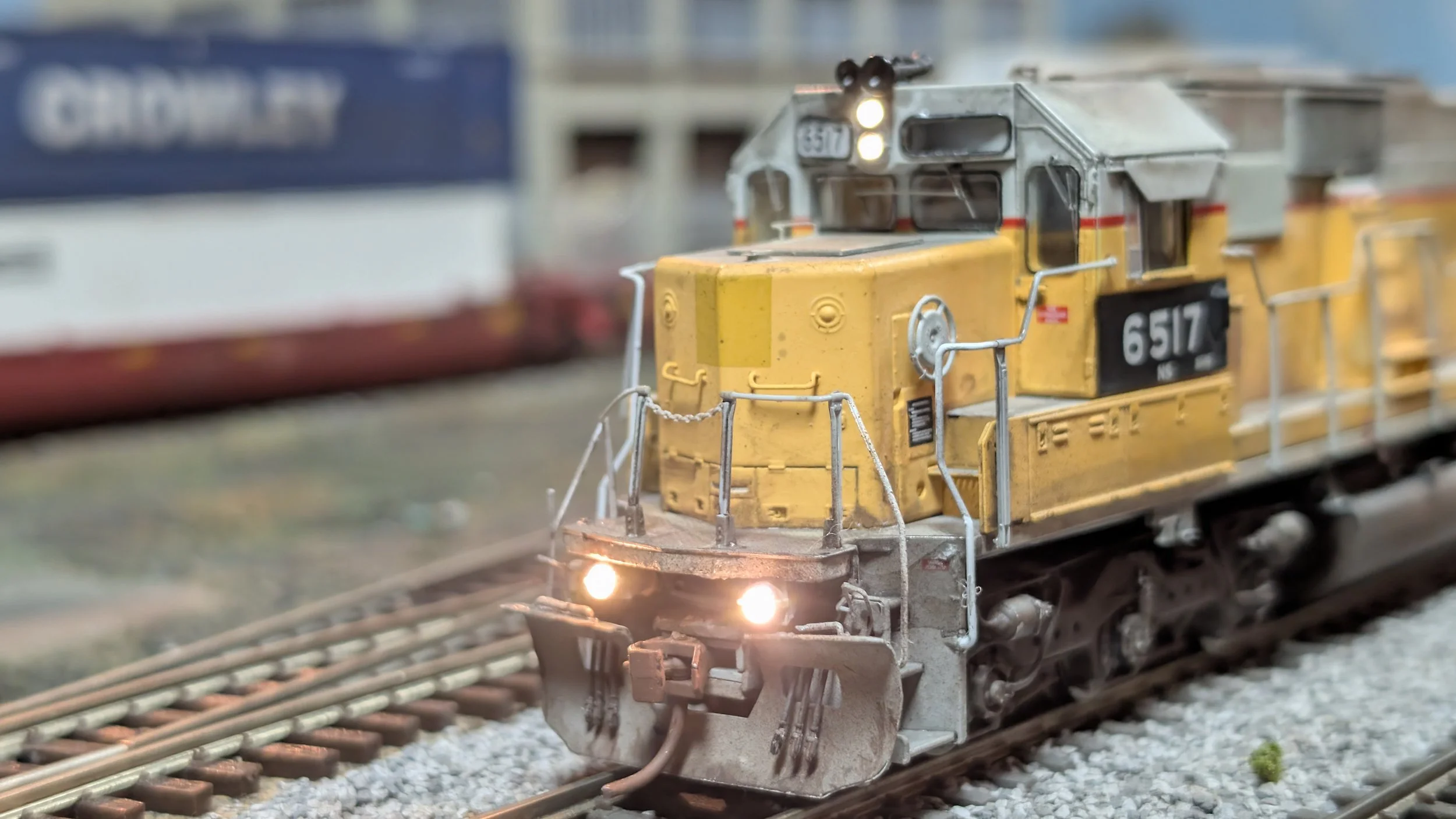 Close-up of a model yellow and gray diesel locomotive train on model railway tracks.