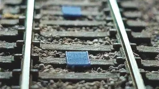 Close-up of train tracks with blue rectangular objects on the wooden ties.