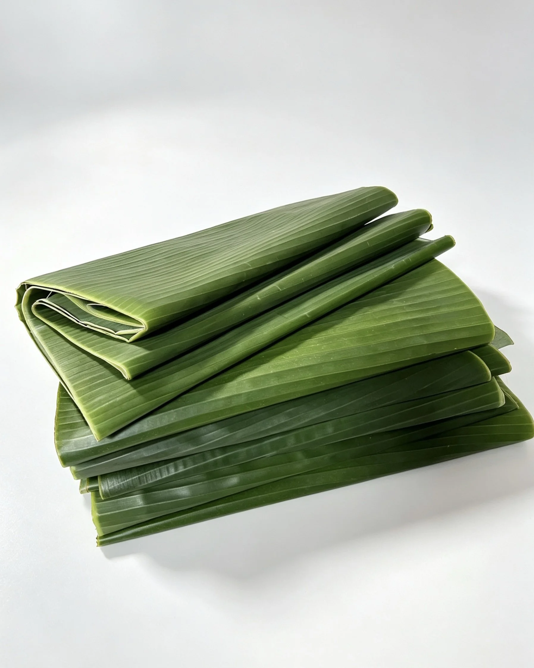 Folded green banana leaves on a white surface.