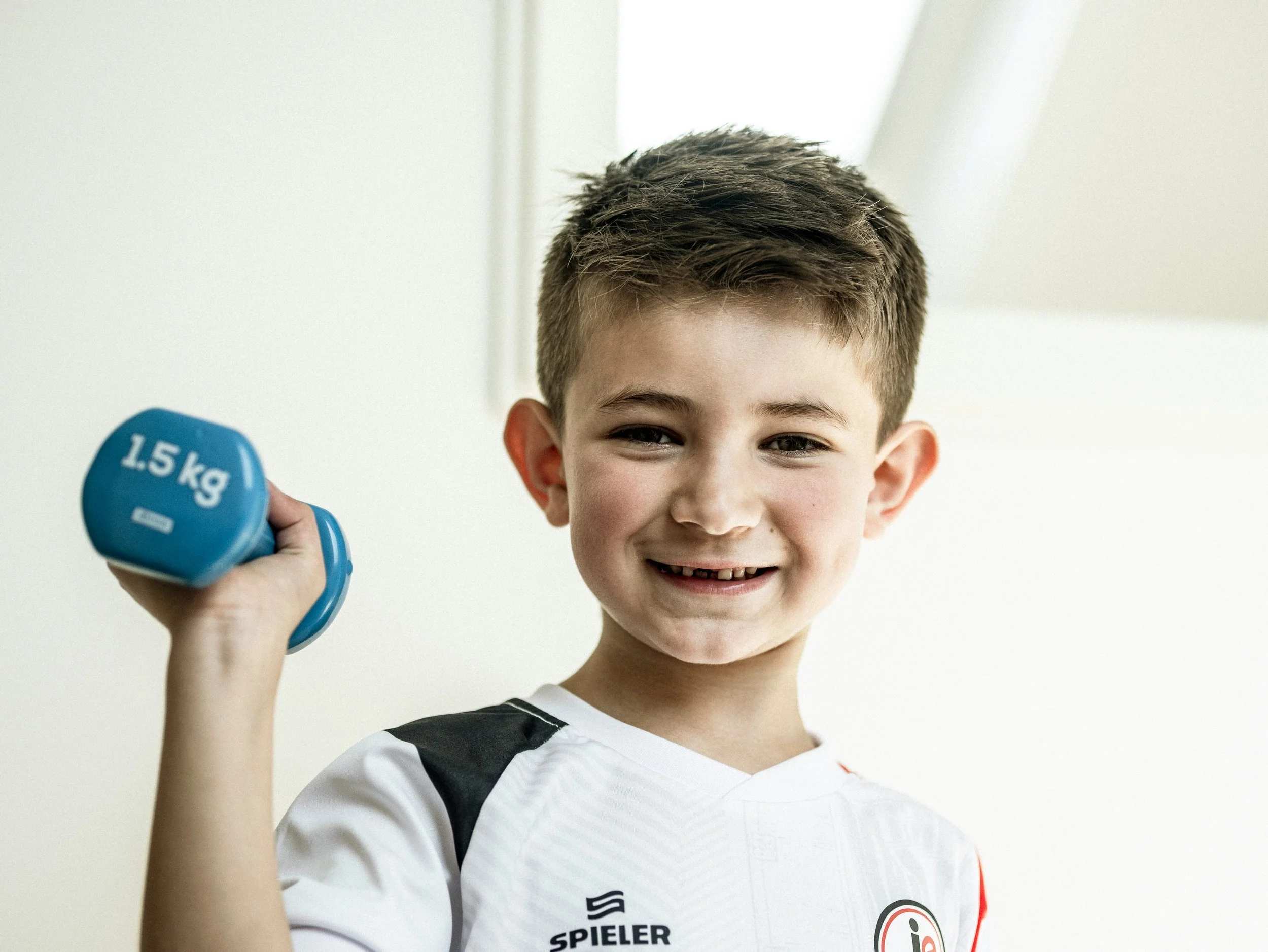 Child exercising with a light dumbbell during physio