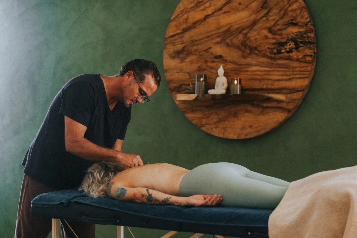 Steven Booth placing acupuncture needles along Lisa Dominey's back in his Byron Bay treatment room
