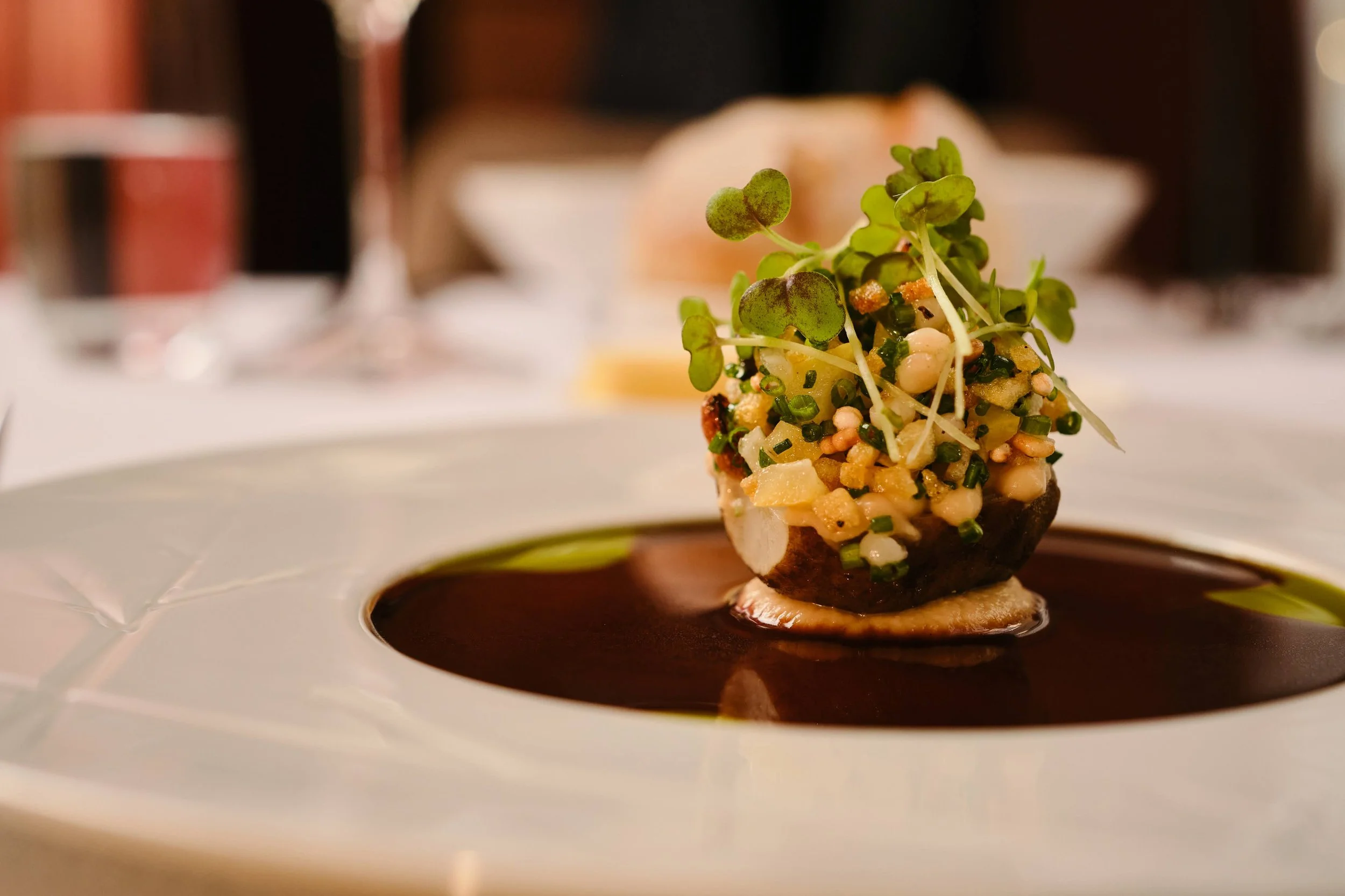 Das Signature-Gericht des Restaurants Blumé in Groningen mit raffinierter Präsentation, dunkler Soße und Microgemüse auf einem weißen Teller