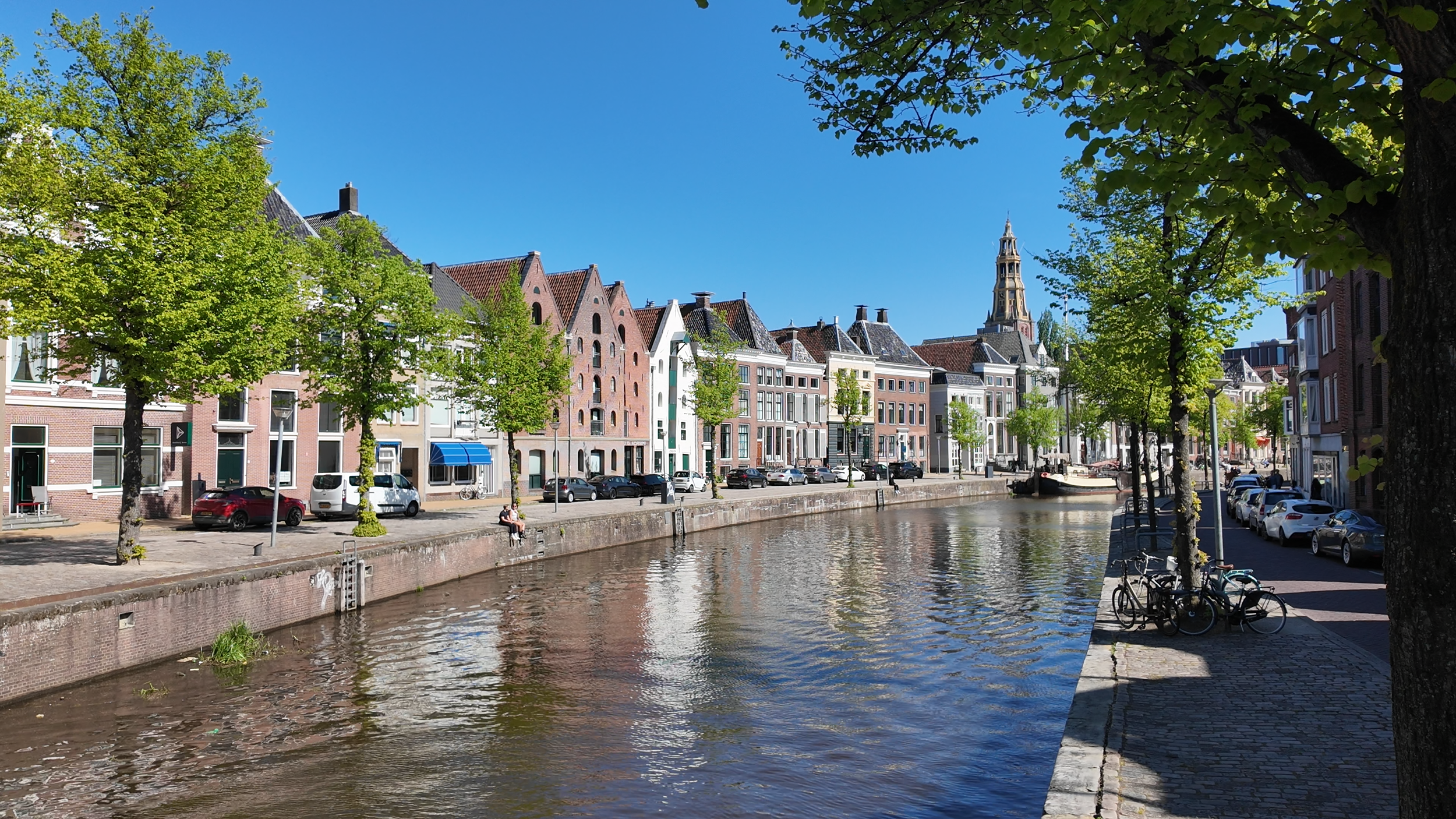 De Aa-kerk en gracht in Groningen op een zonnige zomerdag met historische gevels en bomen langs het water