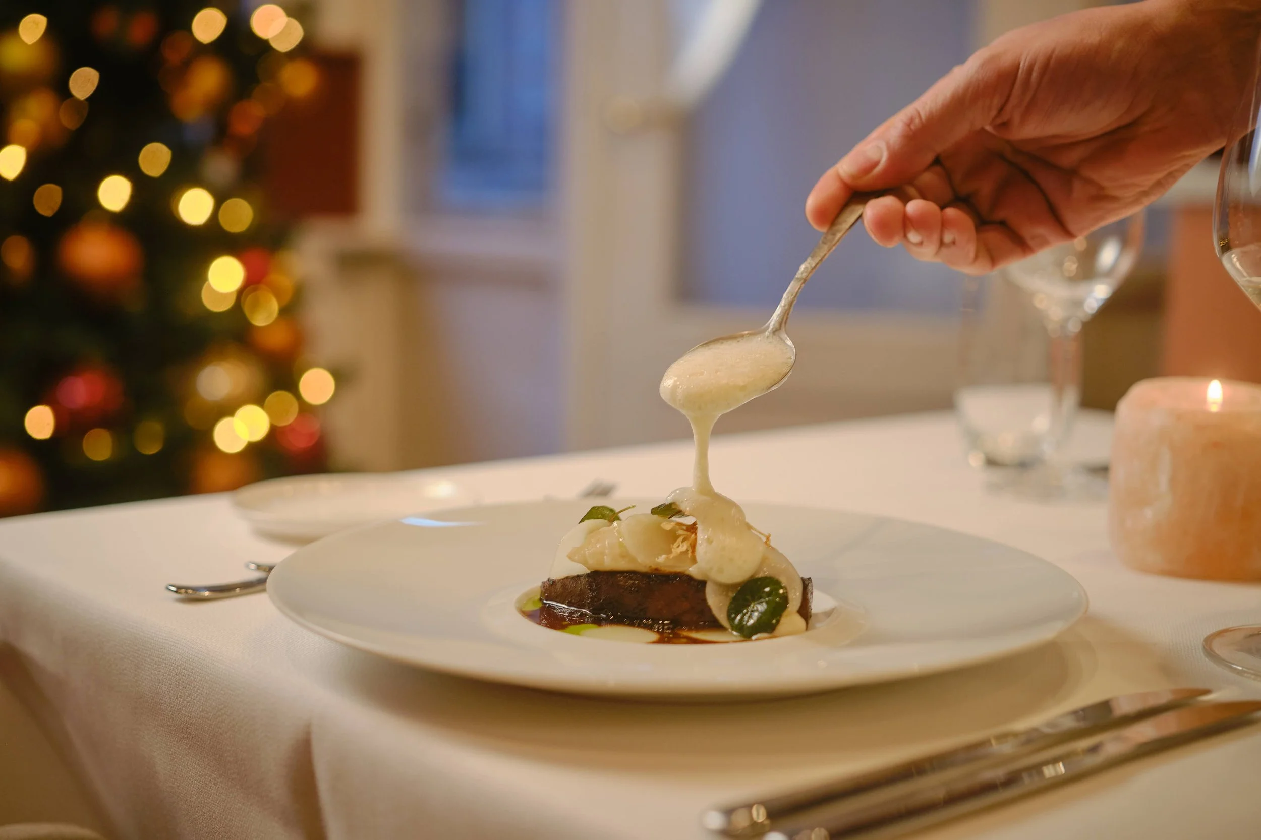 Chef schenkt groene saus over groentegerecht in Restaurant Blumé Groningen, geserveerd in keramische kom met witte wijn en kaarslicht