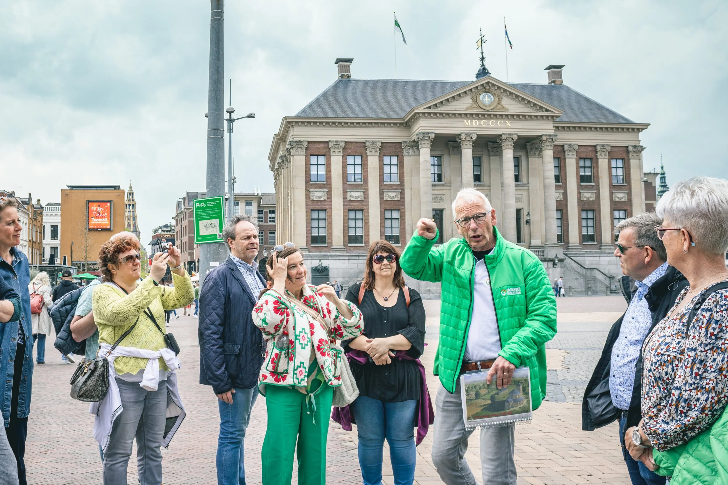 Ein Groninger Stadtführer führt eine Gruppe von Touristen über den Grote Markt in Groningen