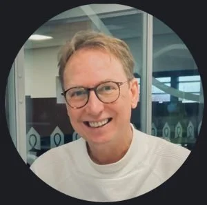 Portrait of a smiling man with glasses in an office setting.