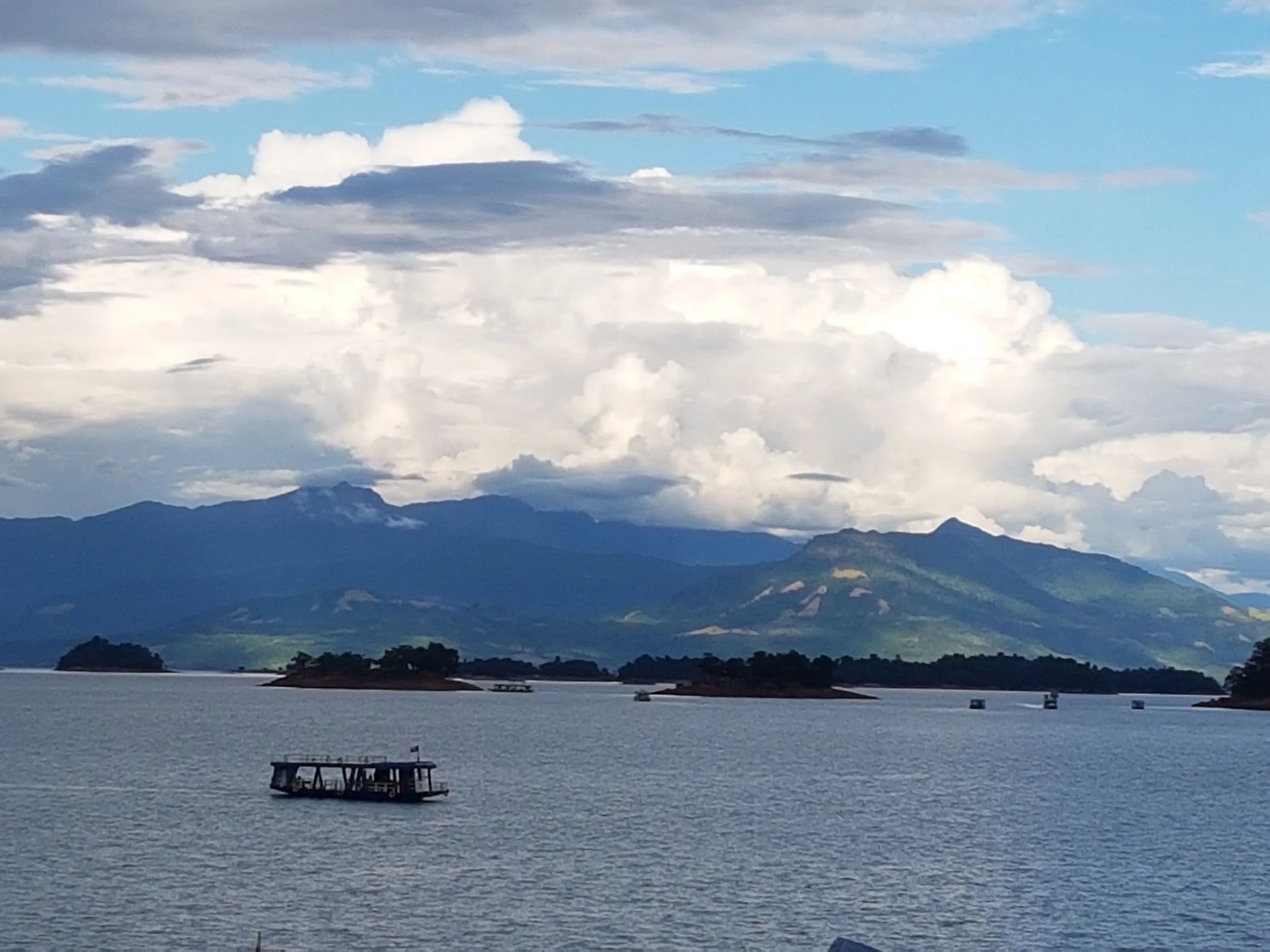 Un lac entouré de montagnes avec un ciel partiellement nuageux.