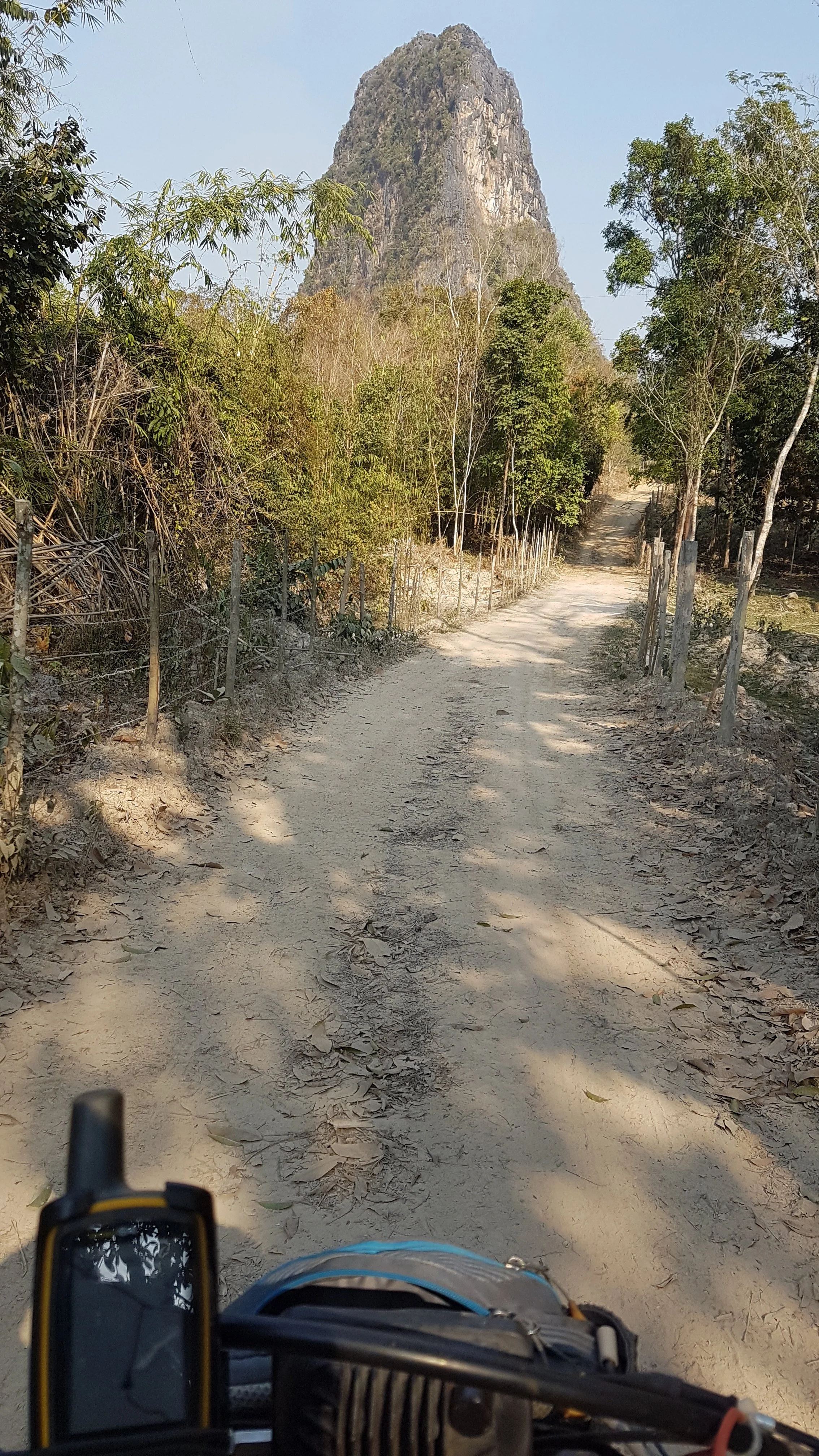 Sentier dirt Road surrounded par arbres avec un grand rocher ou montagne en arrière-plan.