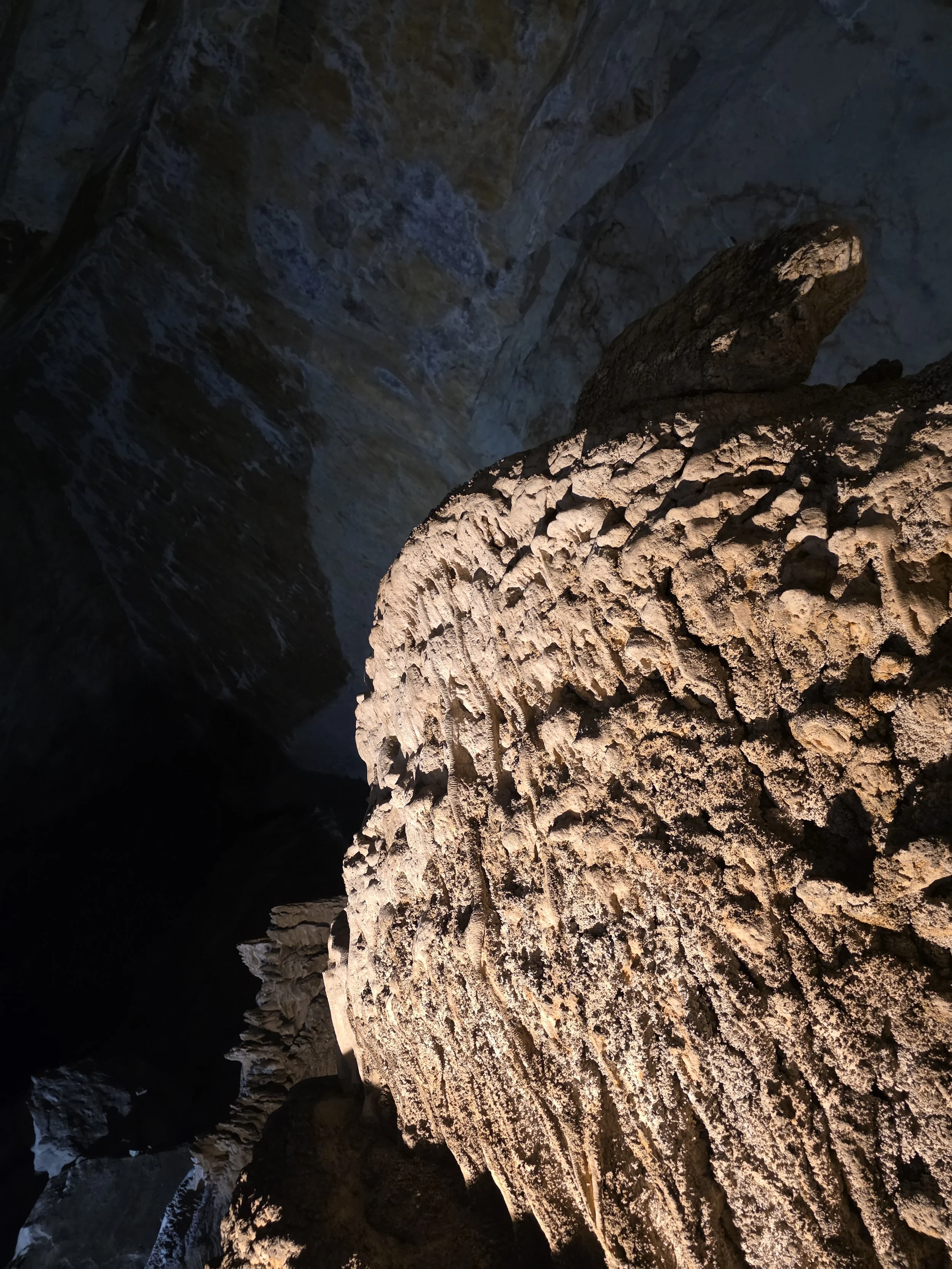 Intérieur d'une grotte avec des formations rocheuses éclairées, vue en contre-plongée.