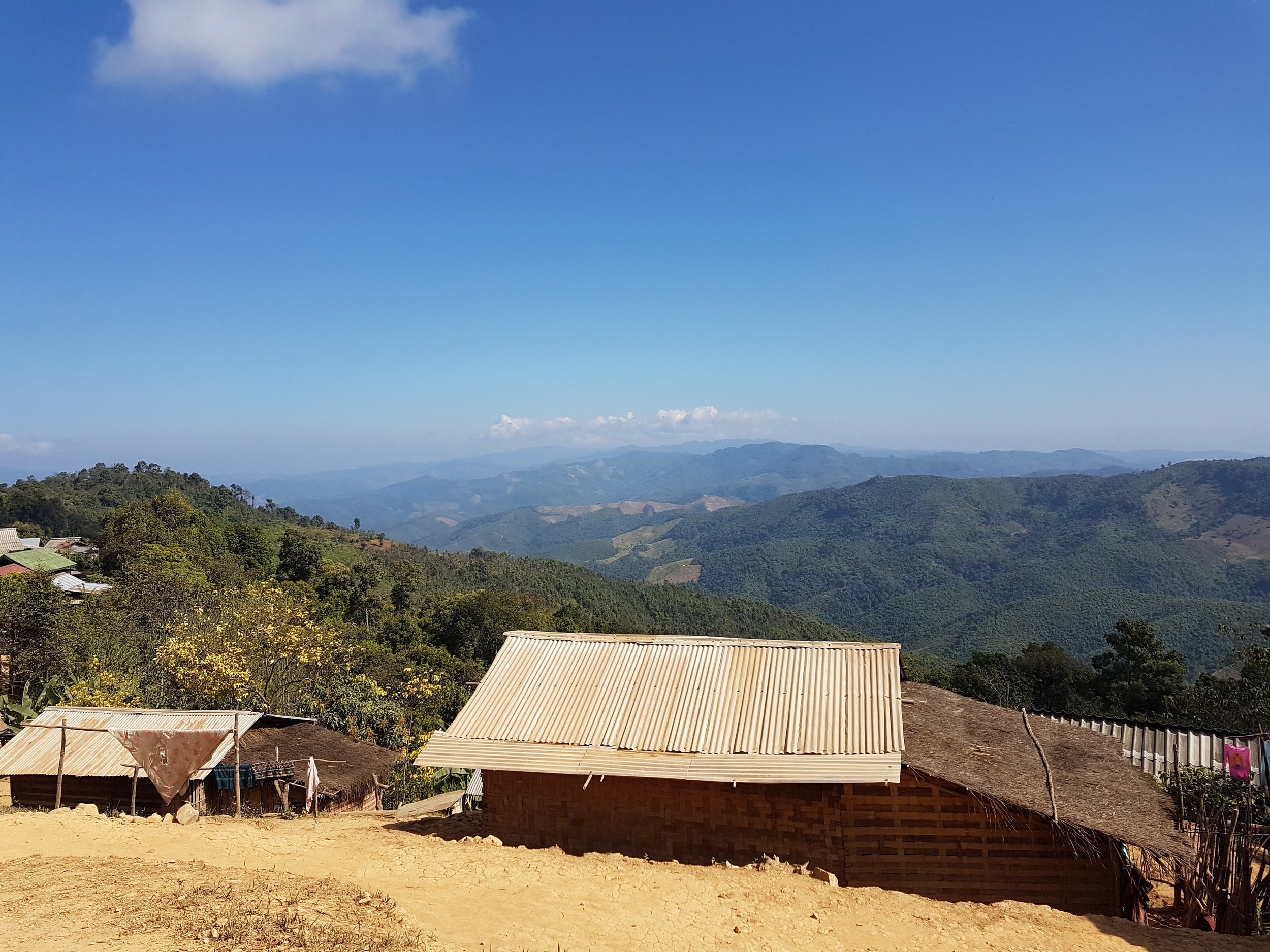 Paysage rural avec des montagnes en arrière-plan, des maisons en r POT et un ciel bleu avec quelques nuages.