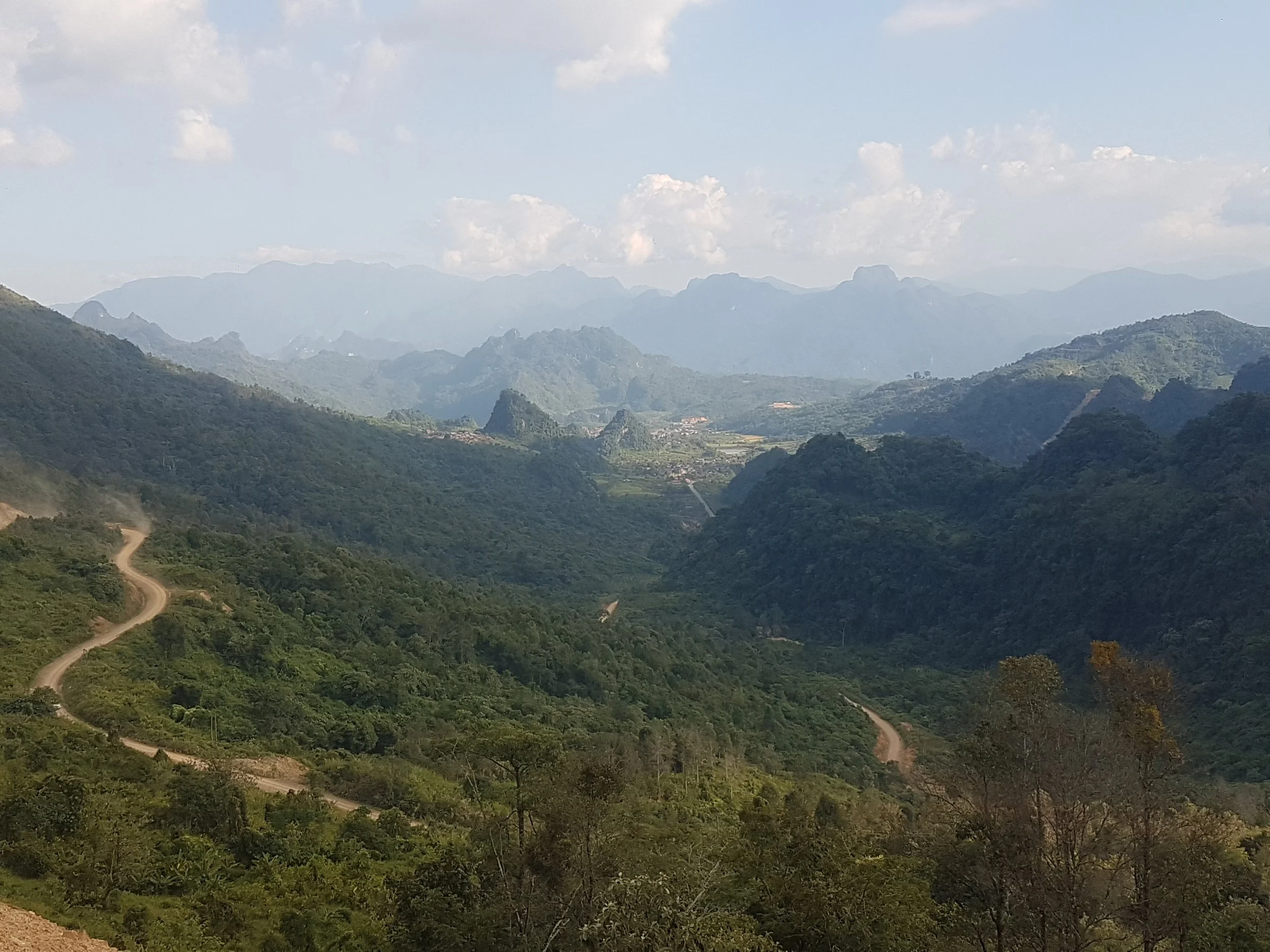 Paysage de montagnes verdoyantes sous un ciel partiellement nuageux.