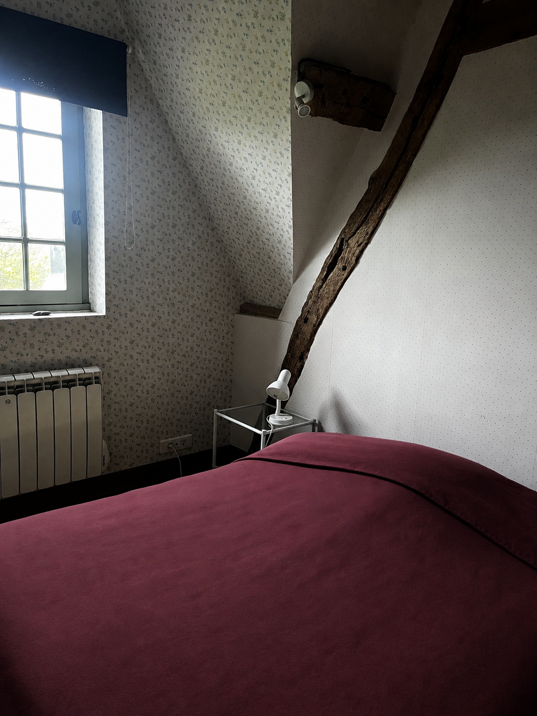 Chambre à coucher sous un toit en angle avec une fenêtre, dans un gite en normandie pour une retraite en septembre 2026