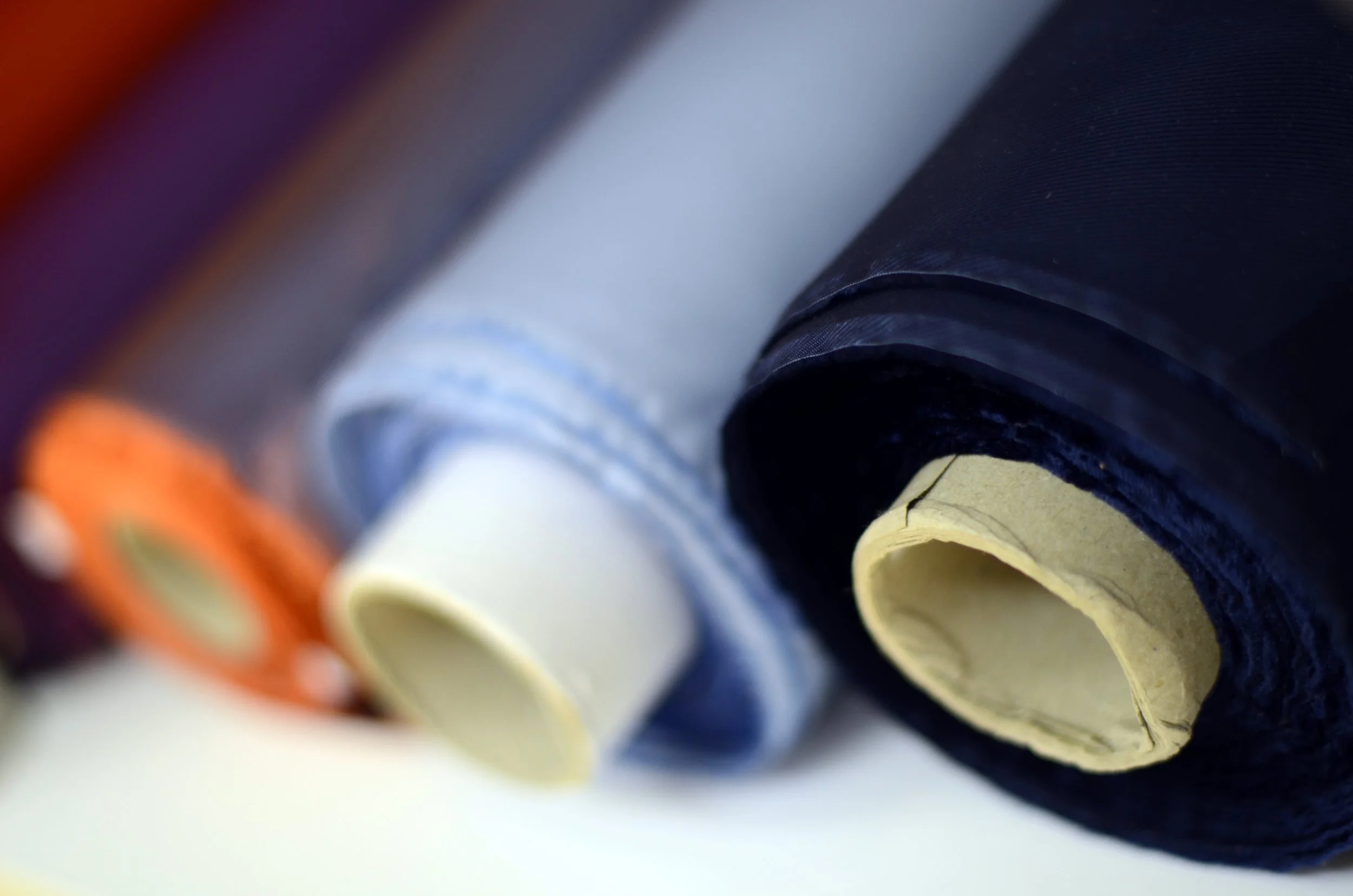 Close-up of rolled-up papers or posters in various colors, arranged in a row.