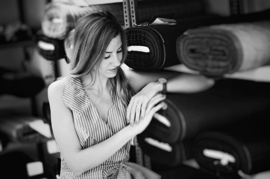 A woman inspecting rolls of fabric in a storage room.