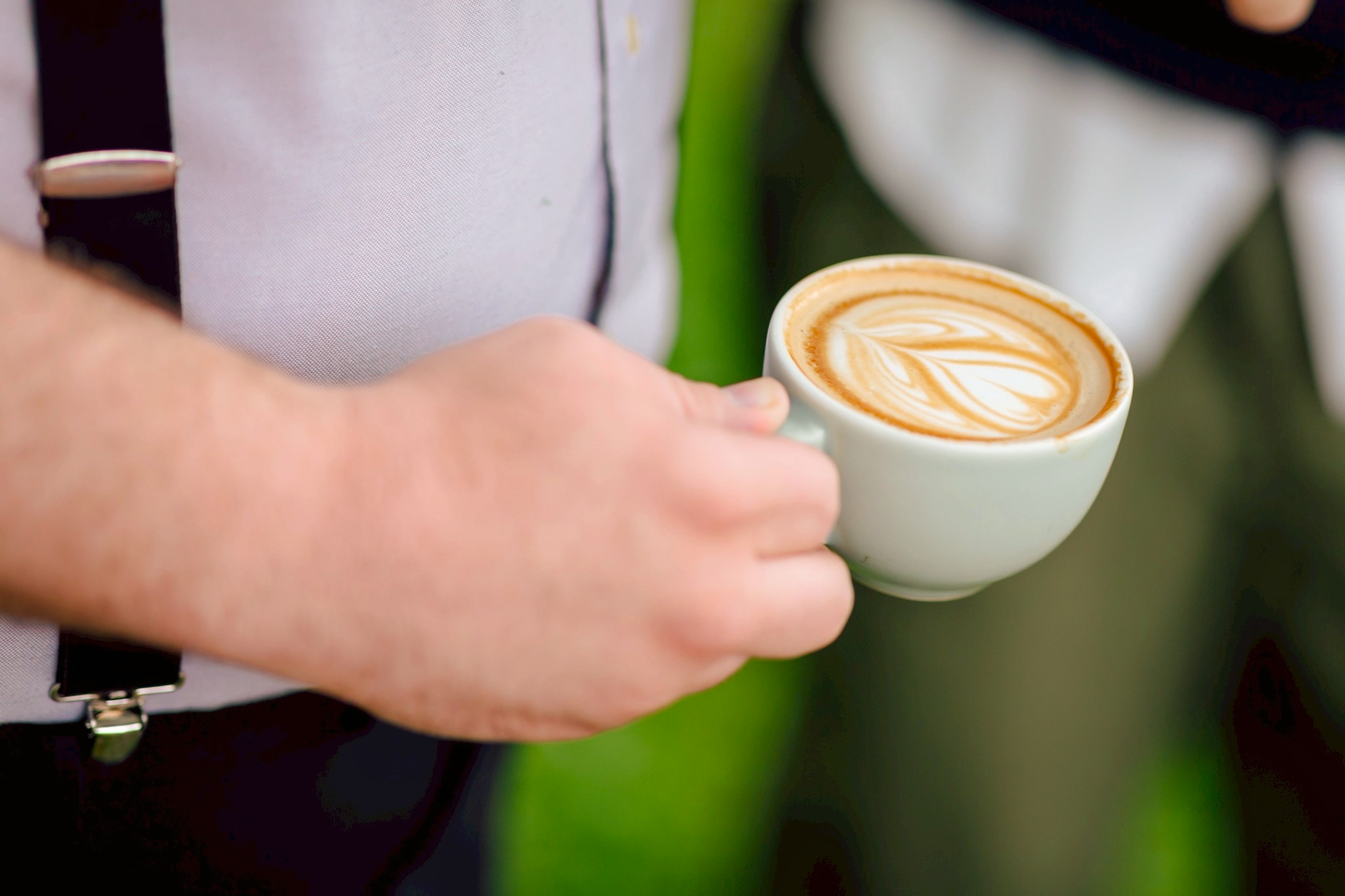 A hand holding a freshly poured latte with intricate latte art, demonstrating the world-class barista skills and local cafe quality curated by Tokyo Coffee Tours.