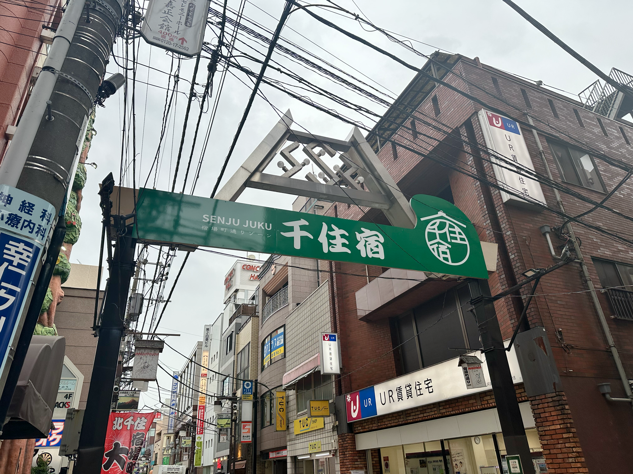 A traditional wooden gate marking the entrance to the historic Senju post town, serving as the physical threshold for the Edo-era time travel experience.