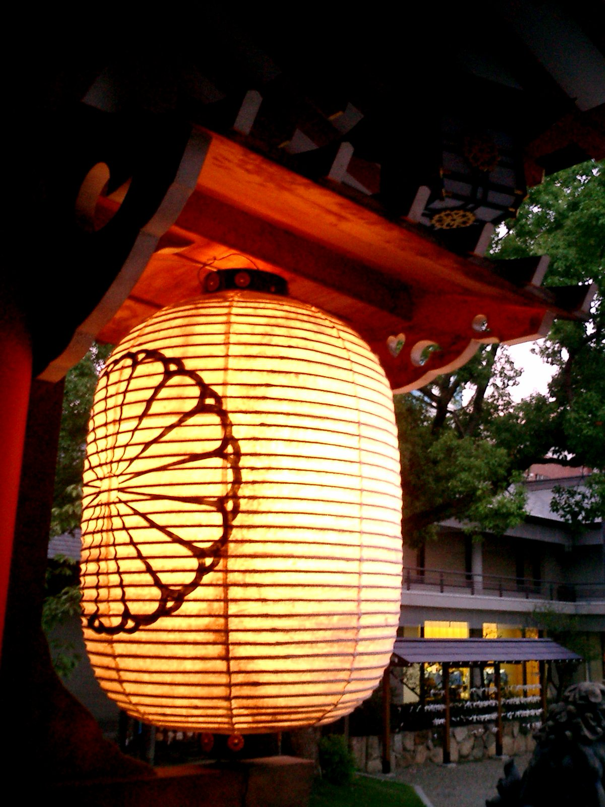 An illuminated traditional Japanese red paper lantern (chochin), a classic cultural symbol often seen outside historic shops and kissaten in Tokyo.
