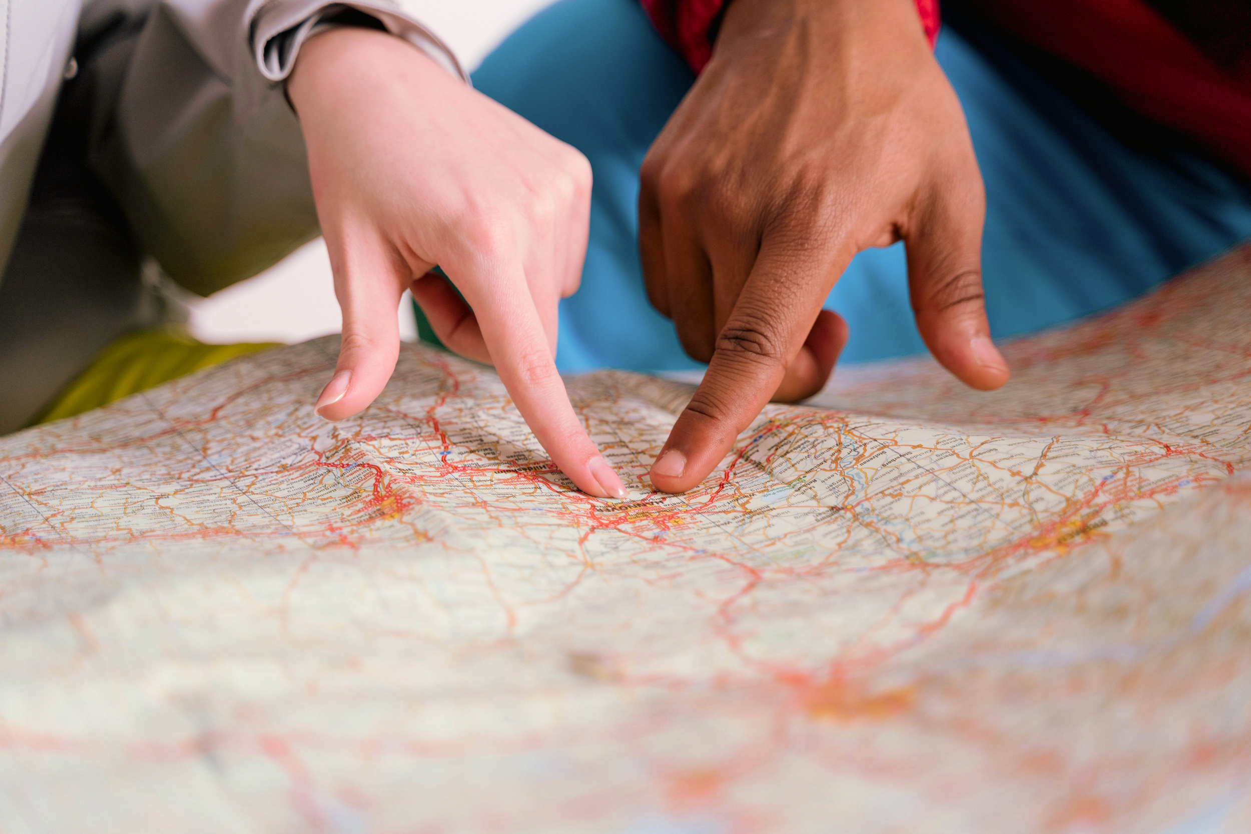 Two people pointing at a physical map, planning a walking route for a guided cafe and coffee shop tour in Tokyo.