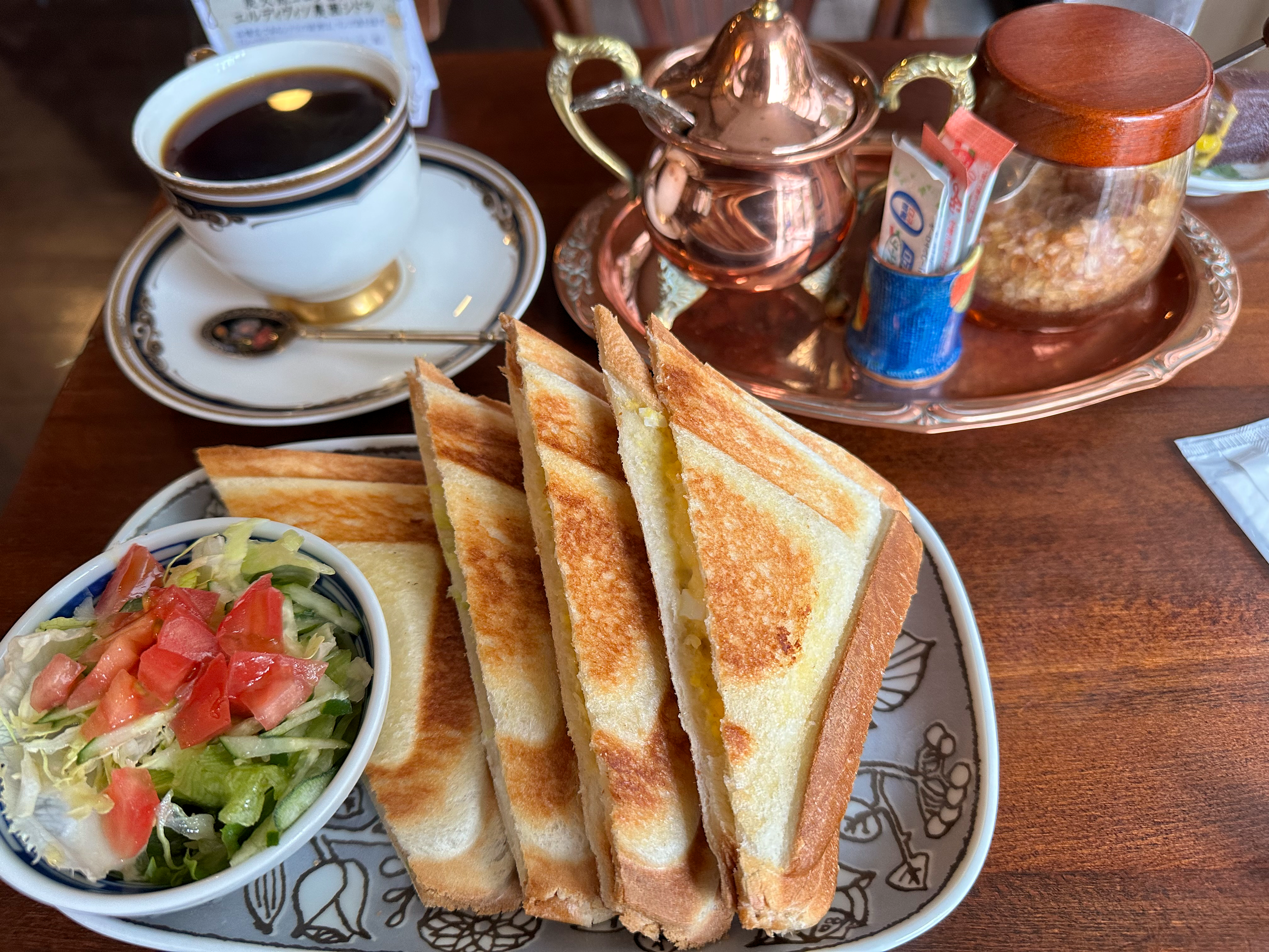 A thick slice of Japanese toast and dark roast coffee served on a wooden table inside a Showa-era kissaten, highlighting the traditional food pairings included on the tour.