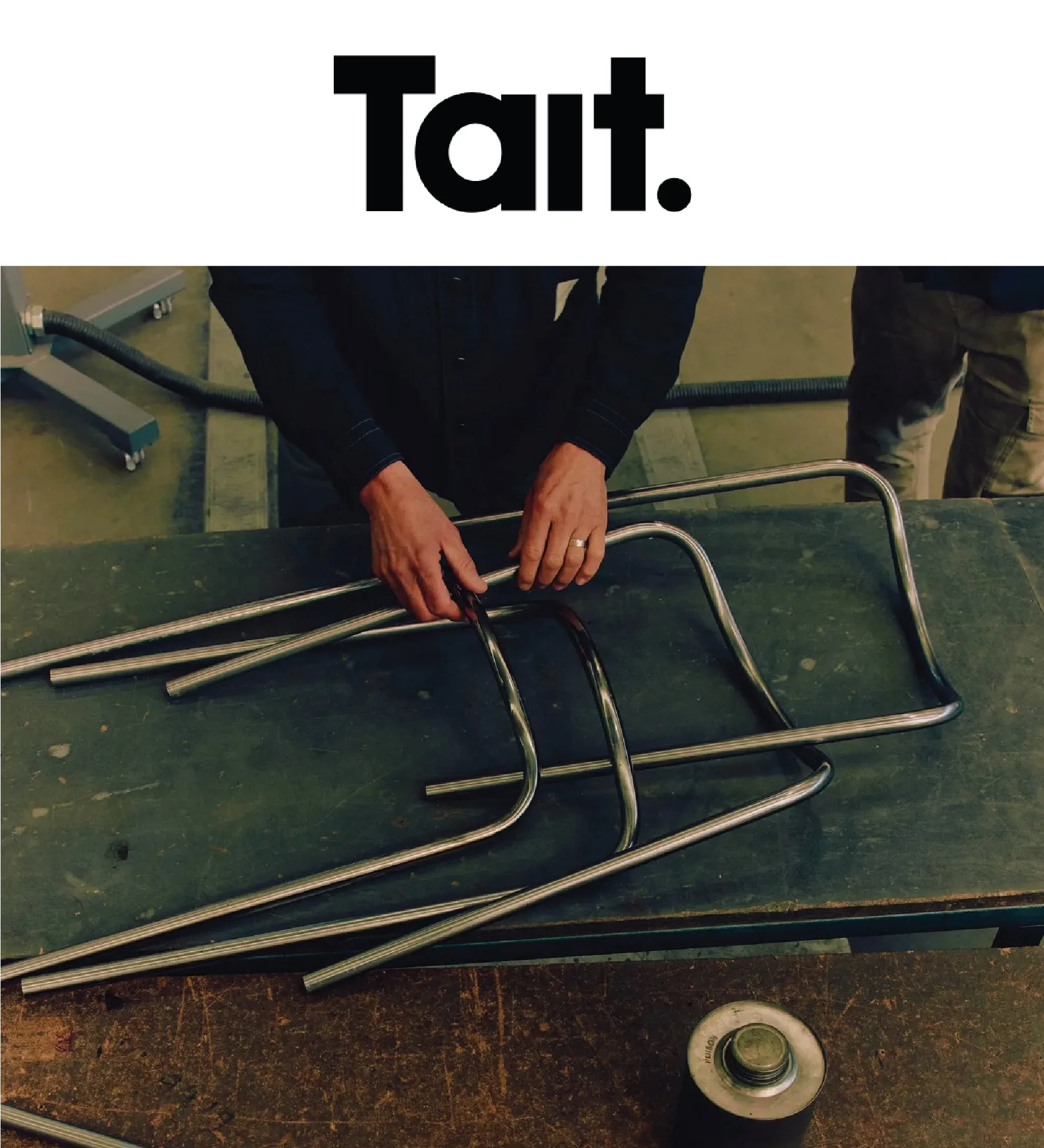 Close-up of a person handling metal pipes, with a roll of tape nearby on a dark, textured surface.