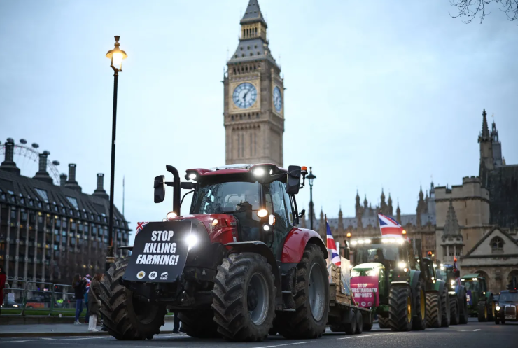 Protesters in farm equipment march in front of Big Ben in London with signs that read 'Stop Killing Farming' and 'Stop Supporting'.