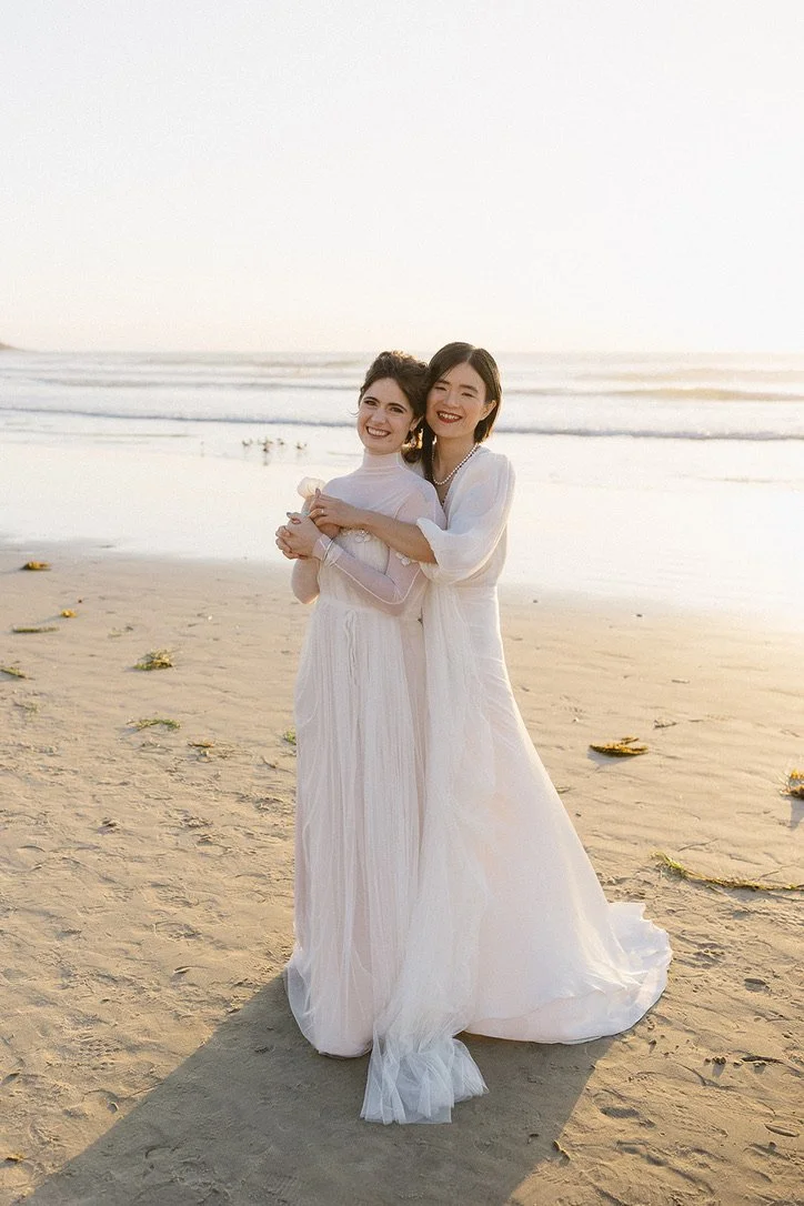two brides hugging on the beach at a la jolla wedding