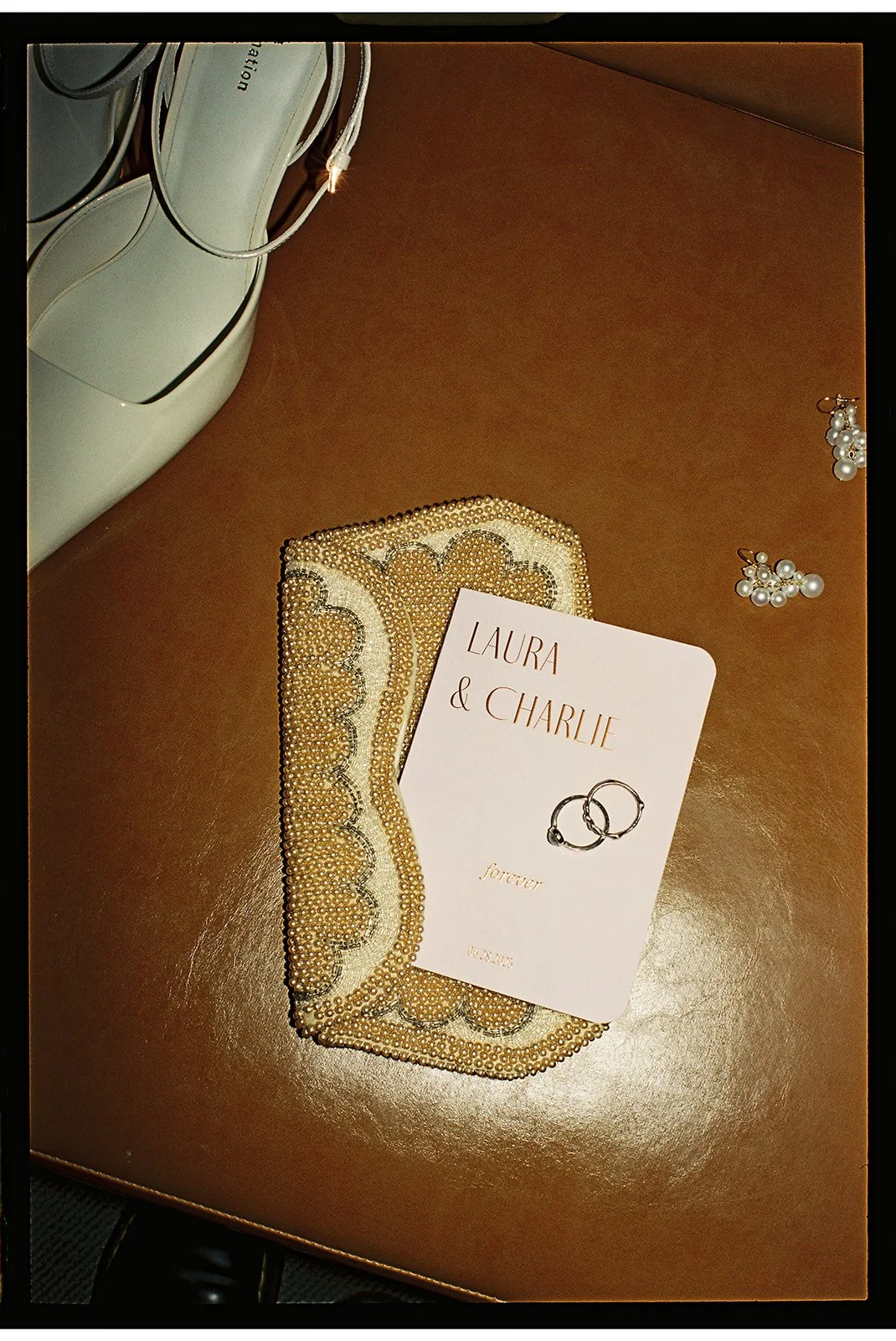 a close up detail of wedding signage for a couple named laura and charlie with shoes, rings and earrings