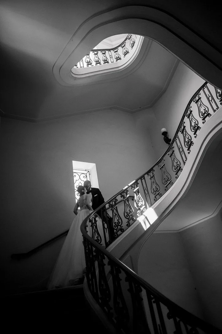 a Jasper and Lane bride and room kissing on the stairs in a black and white photo