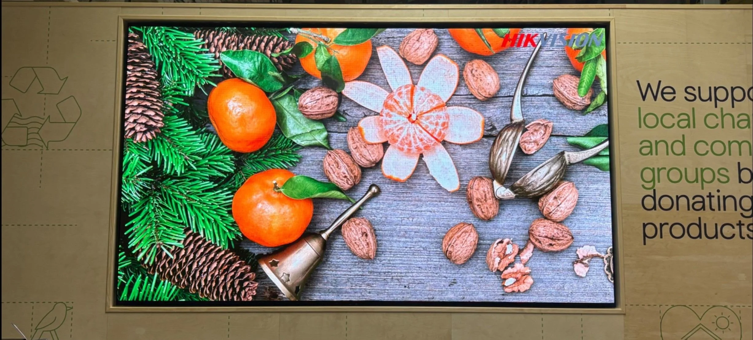 Display with oranges, walnuts, pine cones, and green leaves on a rustic wooden surface, alongside a nutcracker and a flower-shaped orange peel