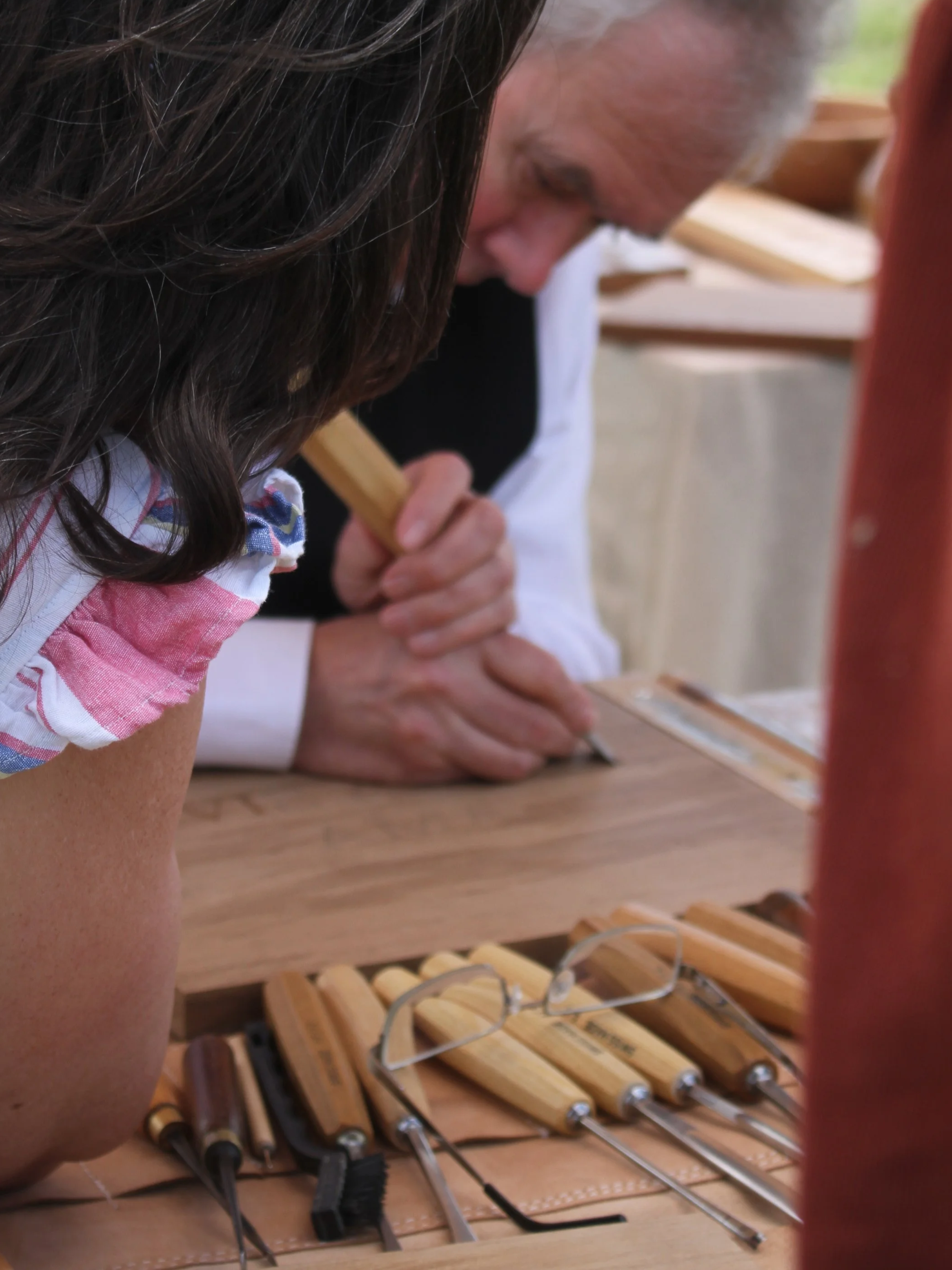 Close-up of two people working on a wooden project, with clamps and tools on a workbench.