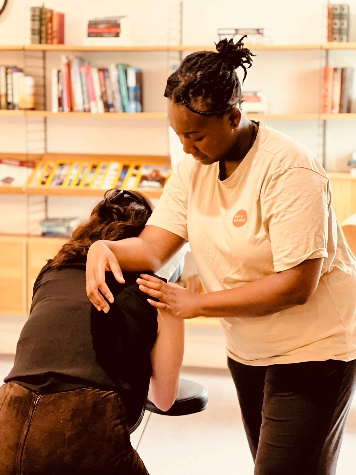 A person receiving a vaccination or shot from a healthcare worker in a room with bookshelves.